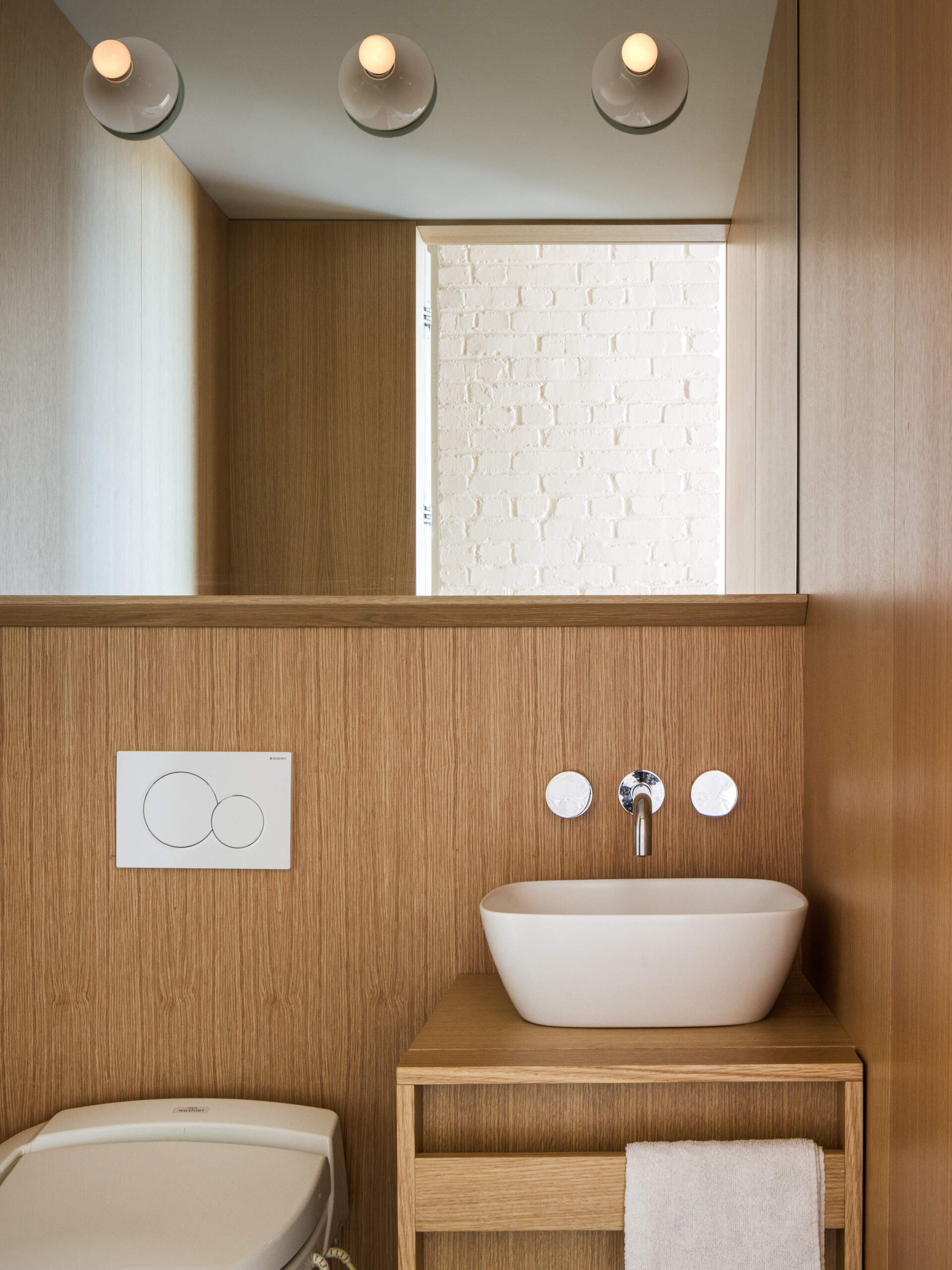 Tucked into a white oak insert, this powder room proves small spaces can still make a statement with thoughtful finishes and seamless integration.