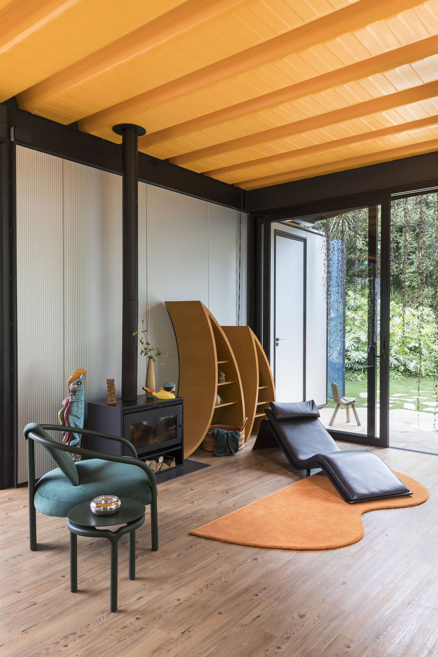 Orange accents, custom furniture, and curtainless windows define the interiors of this joyful weekend home. Everything is designed to feel open, natural, and full of life.