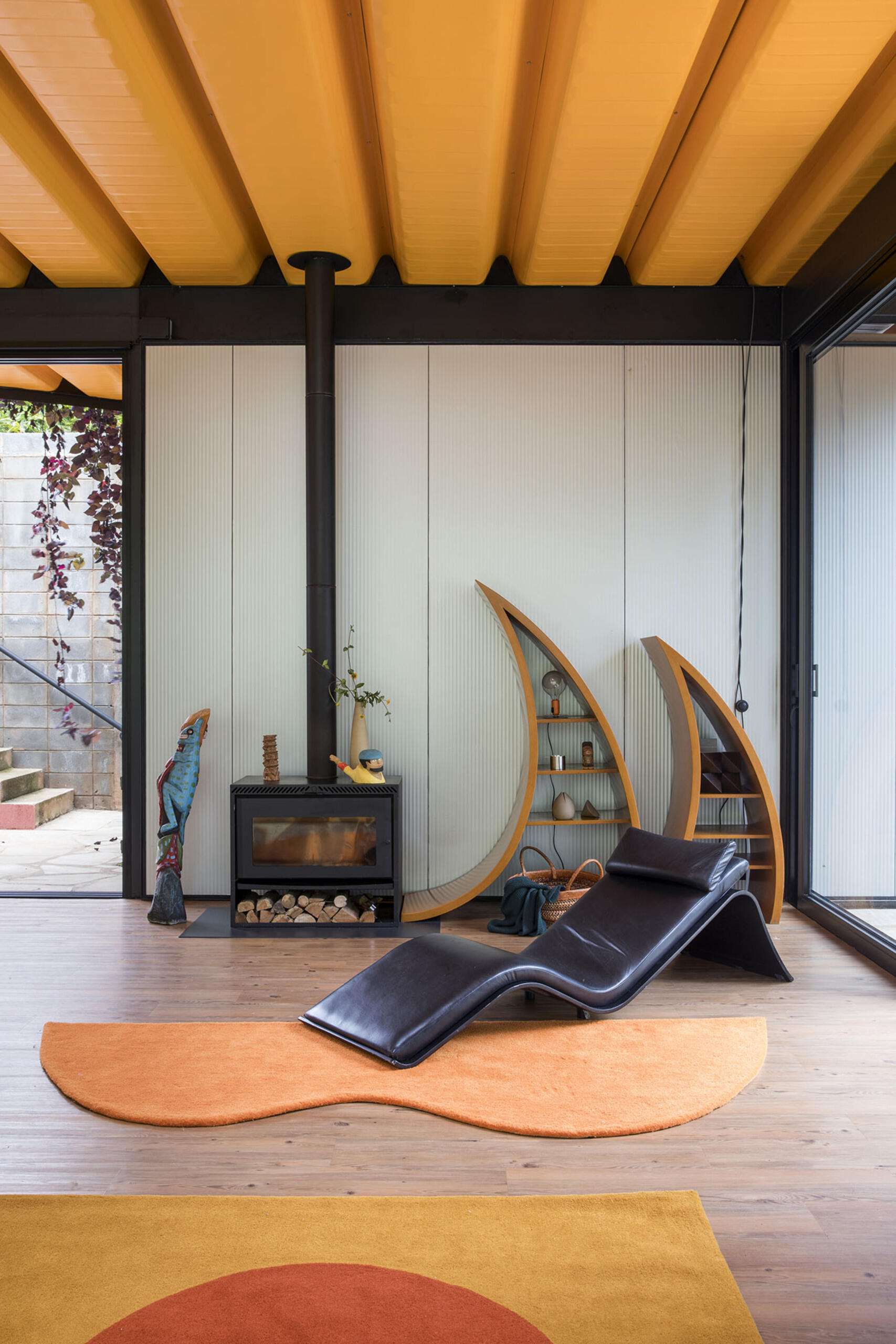 Orange accents, custom furniture, and curtainless windows define the interiors of this joyful weekend home. Everything is designed to feel open, natural, and full of life.