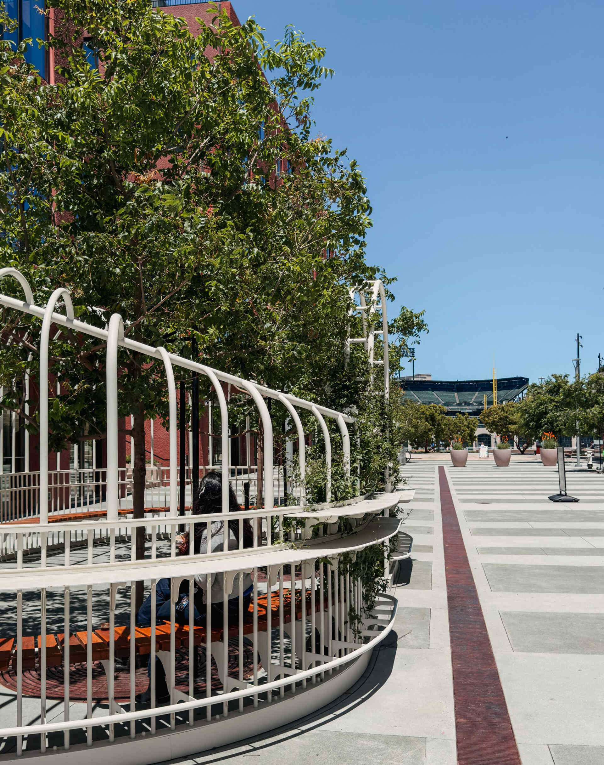 A serene urban pavilion in San Francisco’s Mission Rock, The Garden Party by Min Design reinterprets the Victorian greenhouse as a light-filled public space. With its curving form, custom detailing, and living canopy of integrated trees, this open-air installation invites pedestrians to pause, connect, and enjoy a moment of calm in the city.