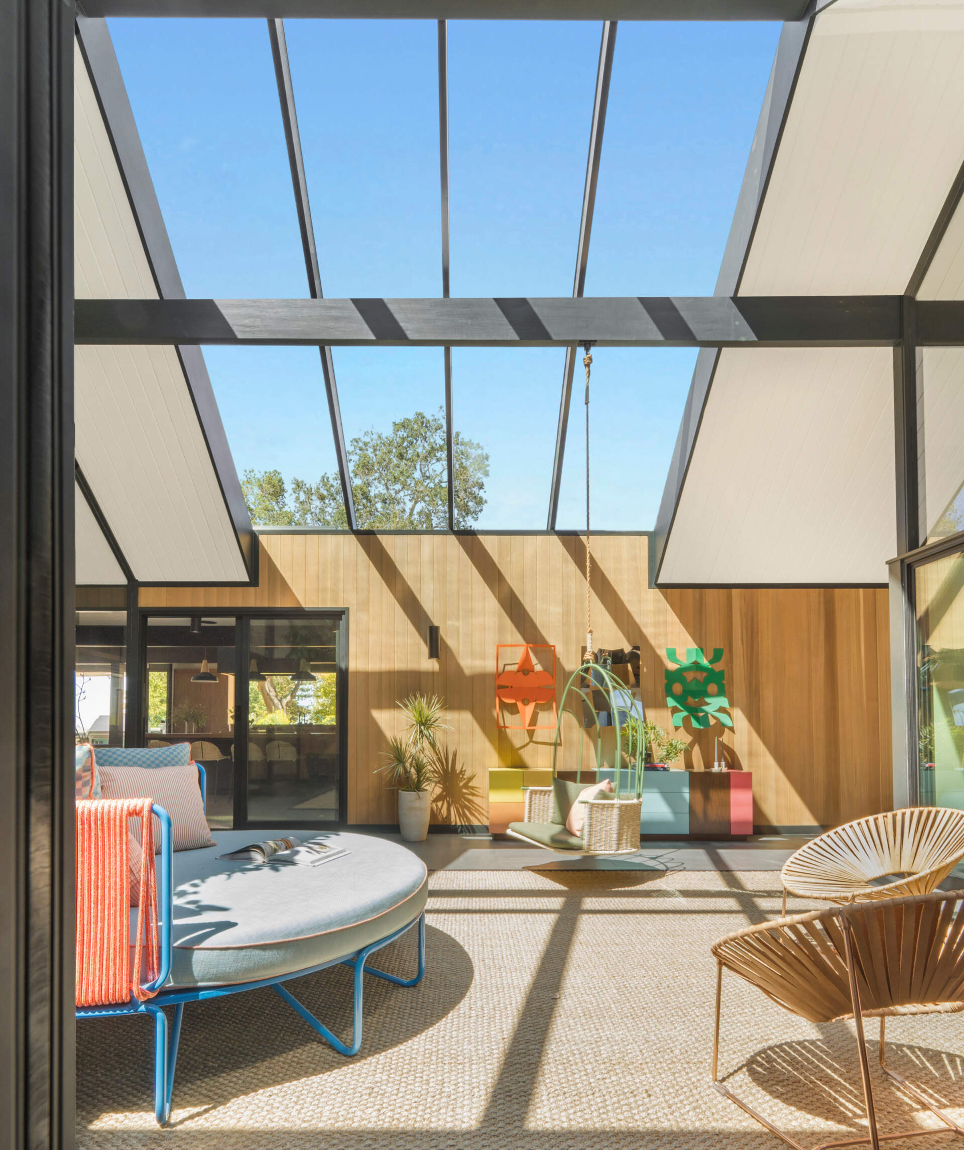 Once open to the elements, the home’s atrium is now enclosed with a glass roof that enhances verticality and floods the interior with natural light. Fleetwood sliding glass doors maintain the visual and physical connection to the outdoors, while western cedar siding gives the space warmth and texture.