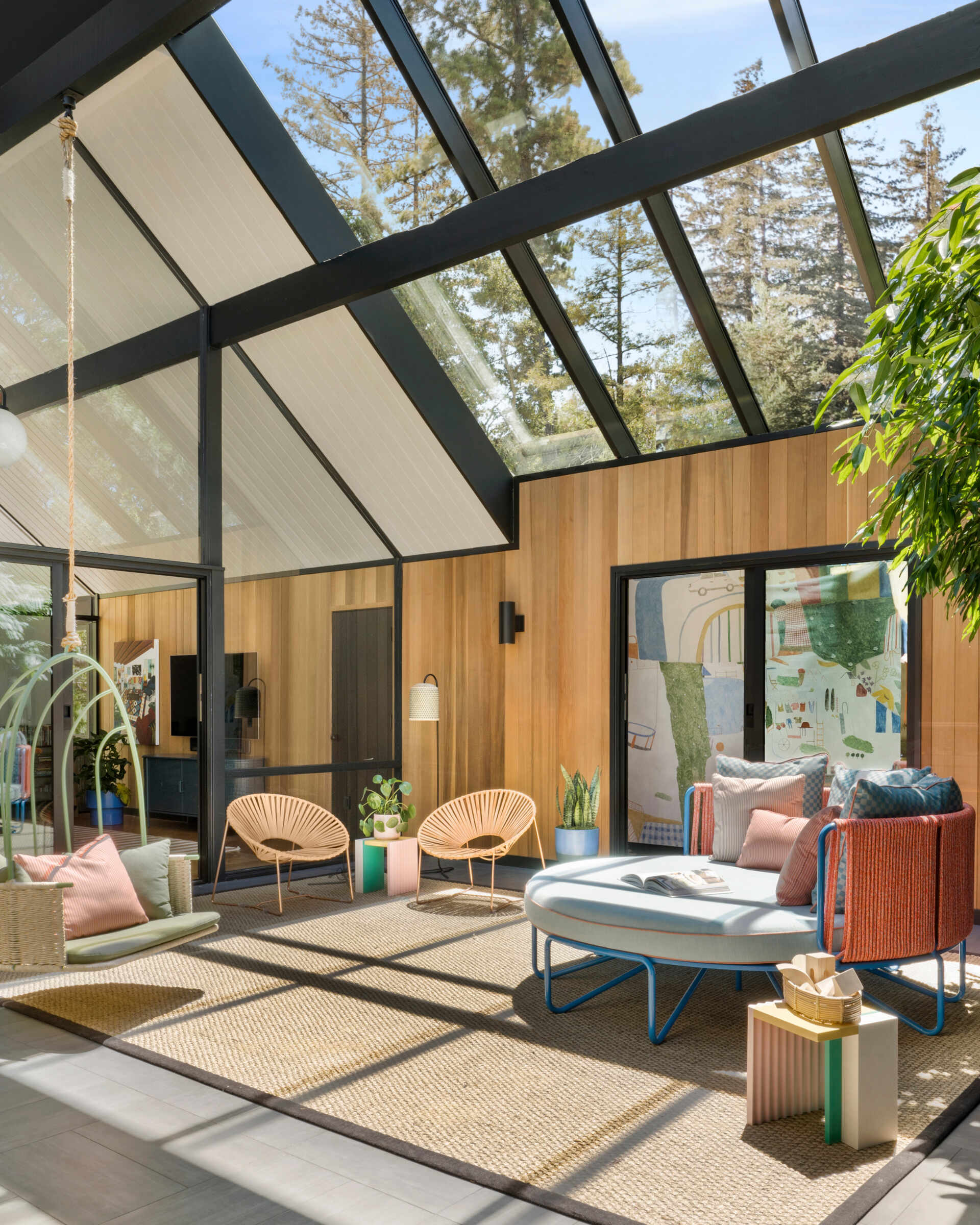 Once open to the elements, the home’s atrium is now enclosed with a glass roof that enhances verticality and floods the interior with natural light. Fleetwood sliding glass doors maintain the visual and physical connection to the outdoors, while western cedar siding gives the space warmth and texture.