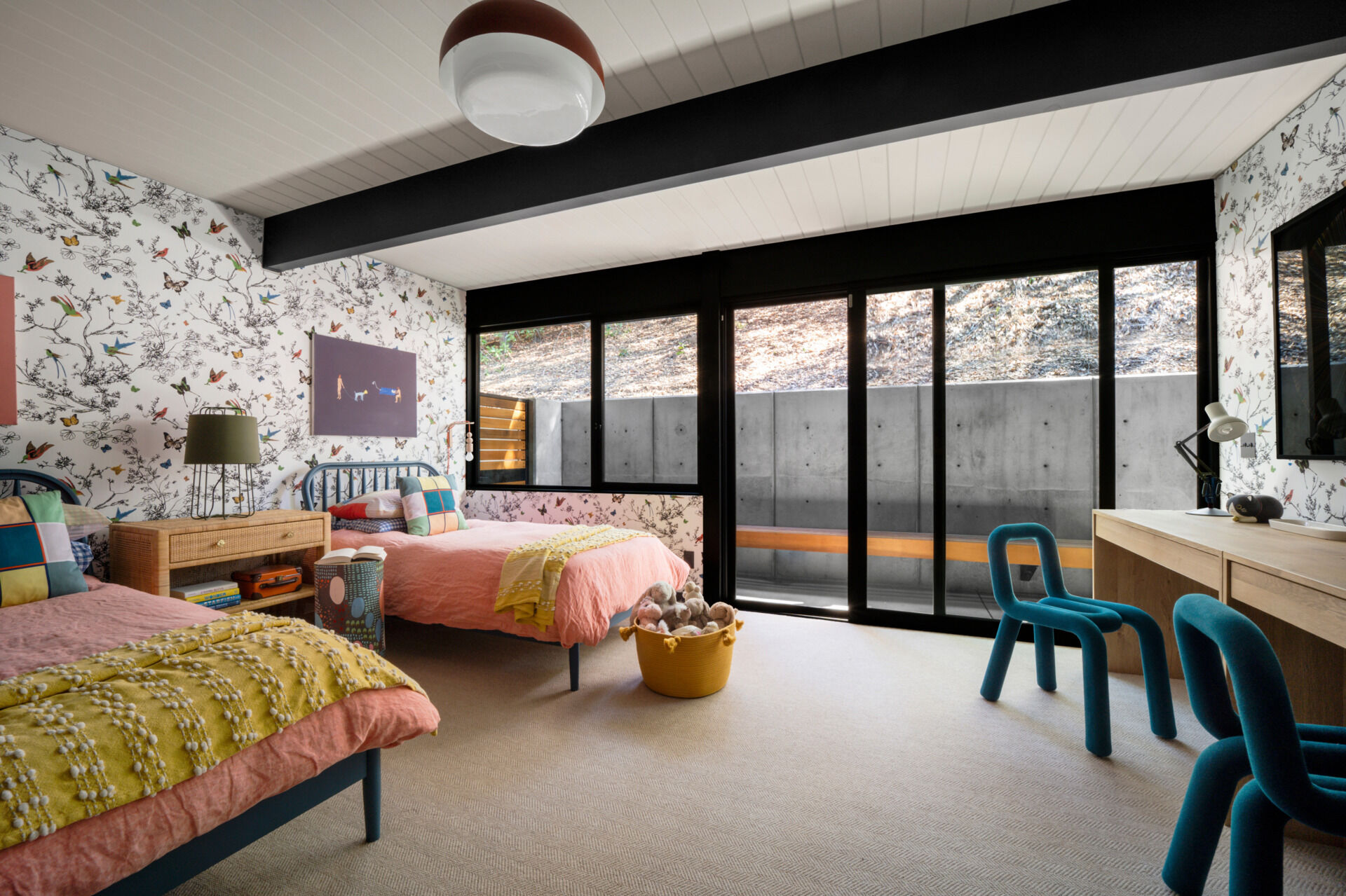 This children's bedroom features sleeping areas and built-in desks. Schumacher butterfly wallpaper adds a whimsical, unexpected flourish to the otherwise clean mid-century aesthetic, delighting one of the family’s daughters.