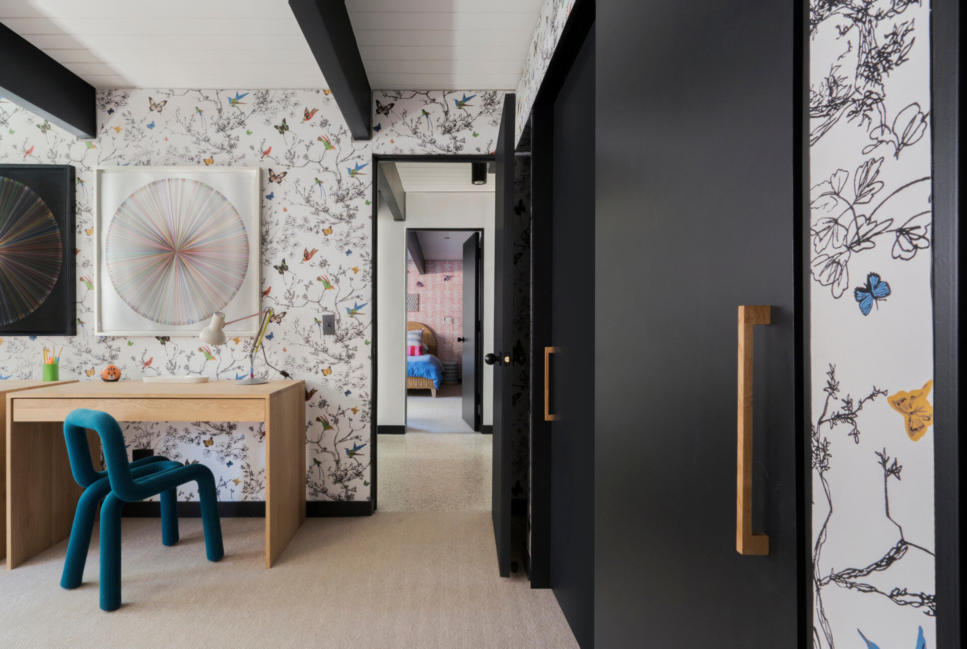 This children's bedroom features sleeping areas and built-in desks. Schumacher butterfly wallpaper adds a whimsical, unexpected flourish to the otherwise clean mid-century aesthetic, delighting one of the family’s daughters.