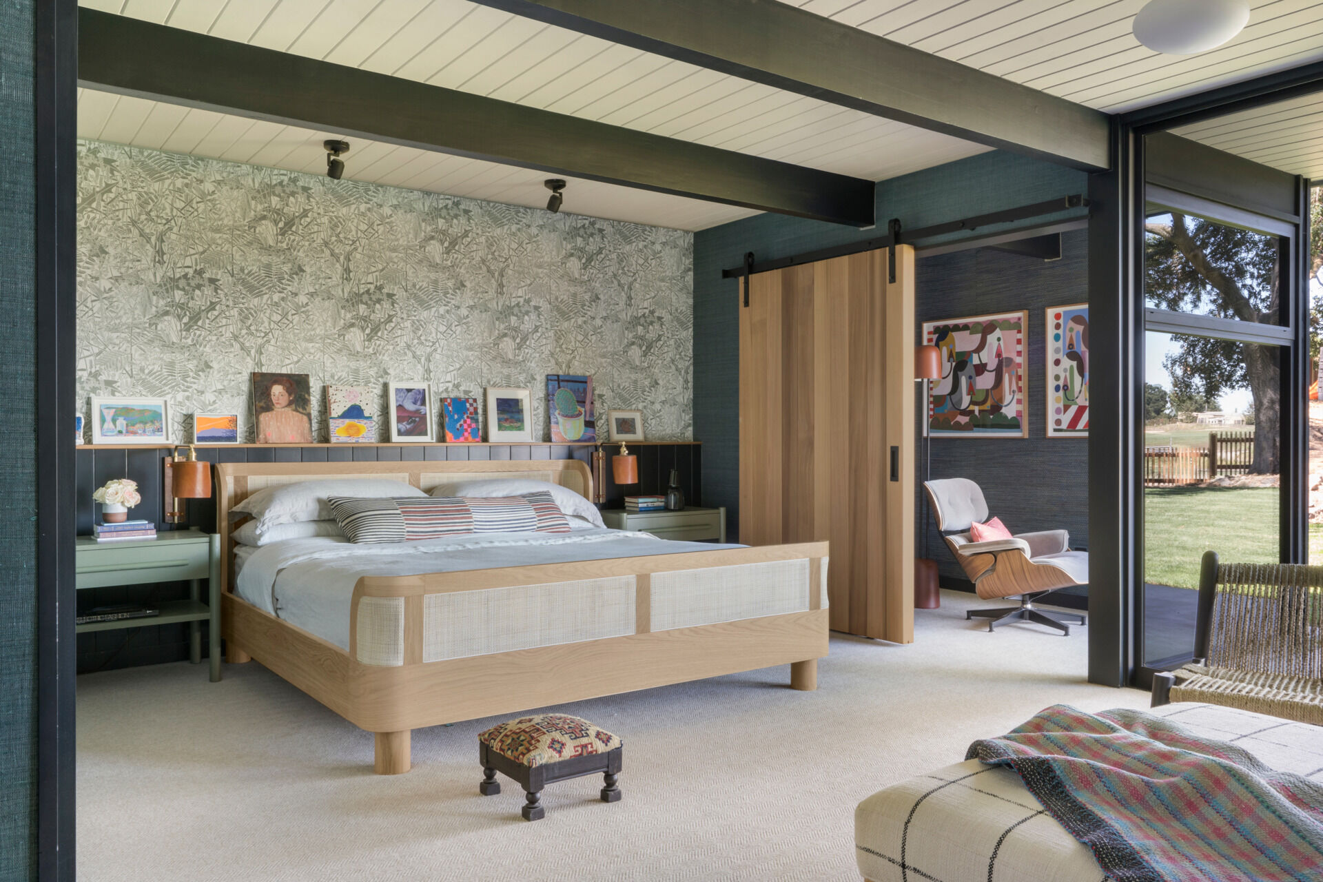In the primary suite, a display ledge and sliding barn door, both crafted from Western Red Cedar, offer thoughtful detailing. The barn door encloses a cozy sitting area, which opens via floor-to-ceiling retractable Fleetwood glass doors to the garden beyond.