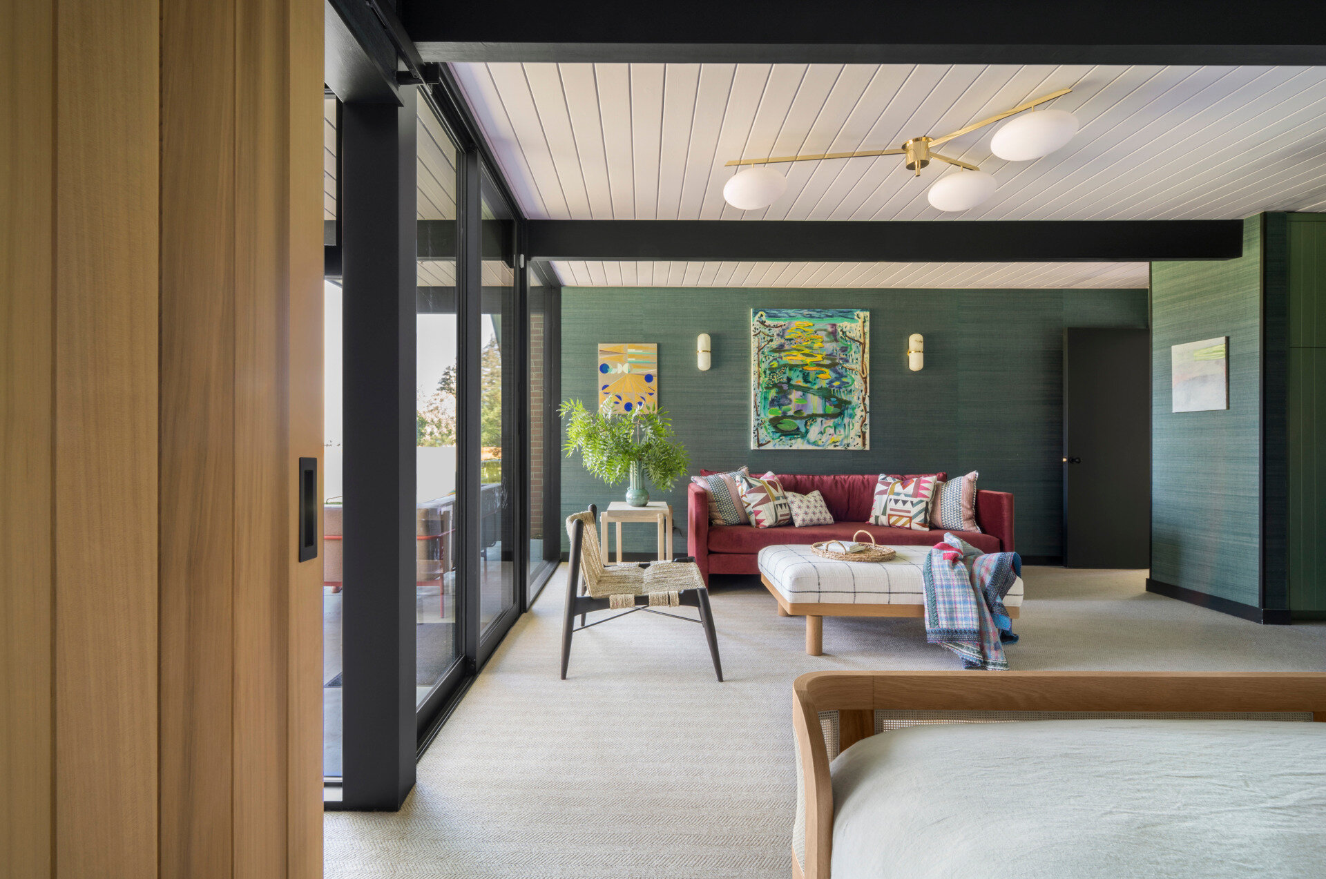 In the primary suite, a display ledge and sliding barn door, both crafted from Western Red Cedar, offer thoughtful detailing. The barn door encloses a cozy sitting area, which opens via floor-to-ceiling retractable Fleetwood glass doors to the garden beyond.