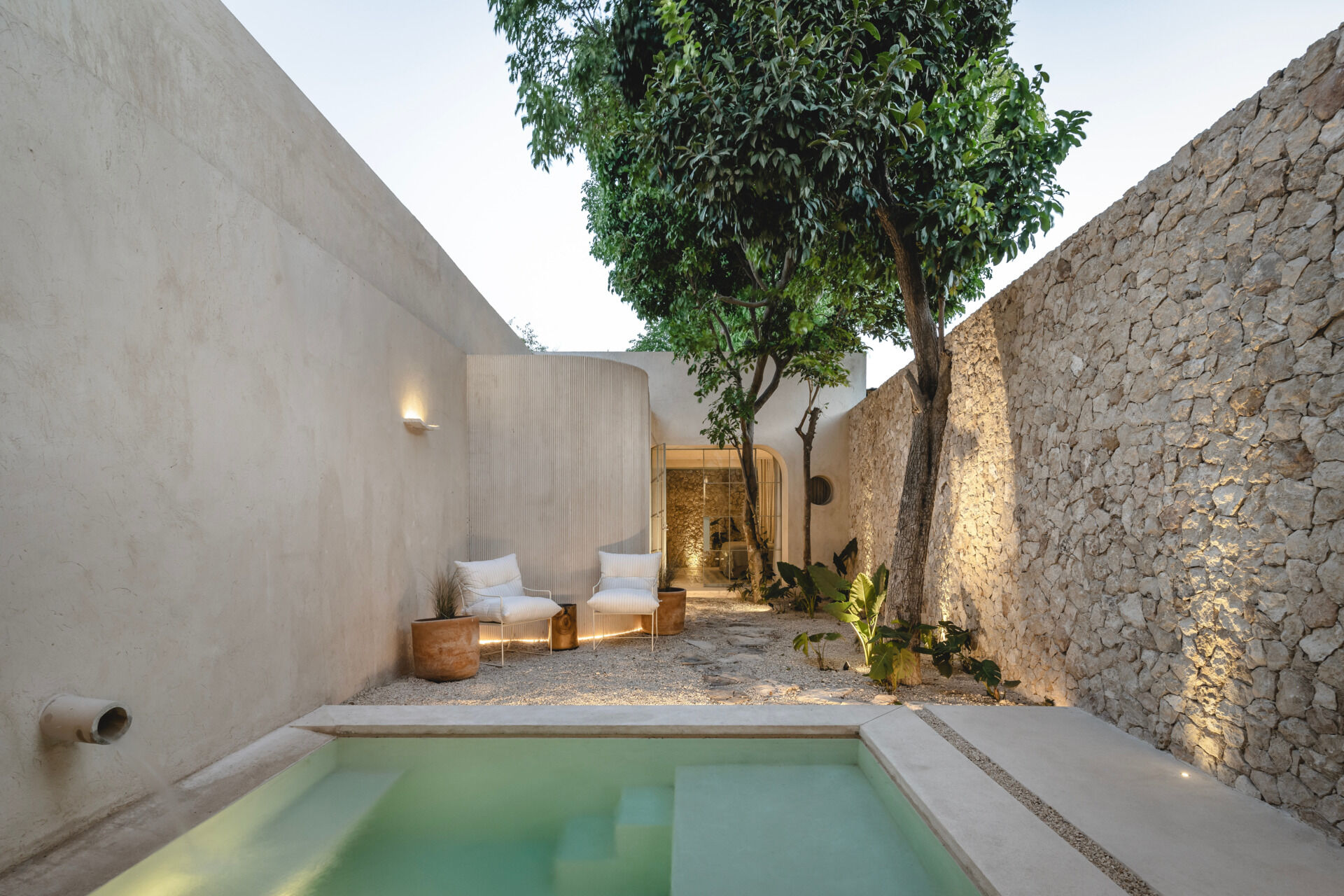 Tucked into the rear garden, the pool offers a cool, shaded retreat. Its placement at the end of the spatial sequence creates a sense of discovery, and its simple geometry mirrors the clean lines of the architecture. Surrounded by regional stone and soft landscaping, the pool blends into its setting while offering visual contrast and a place to unwind.