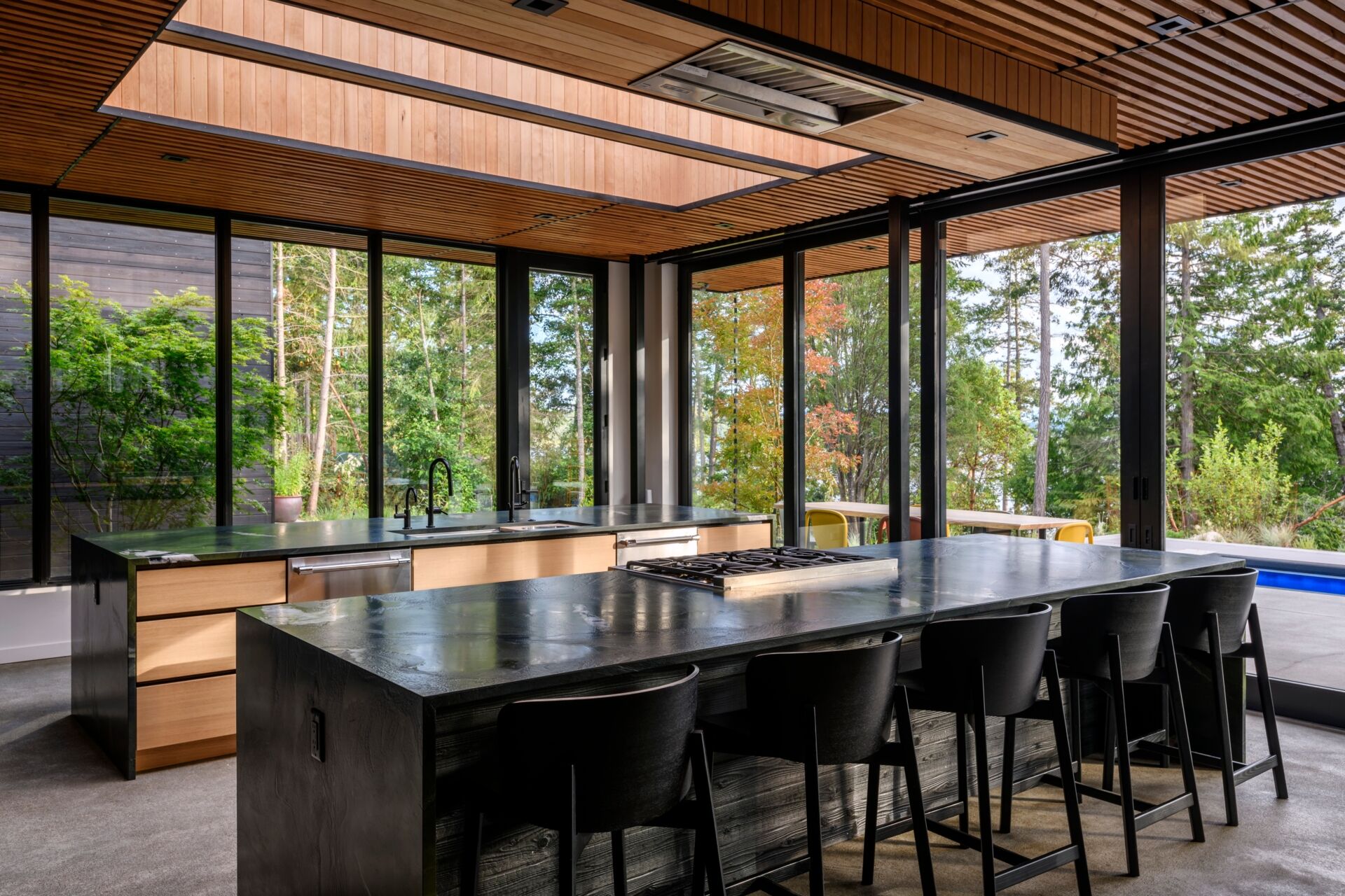 An open plan kitchen with two islands and skylights, is built for gathering, with clean lines, ample light, and strong indoor-outdoor flow.
