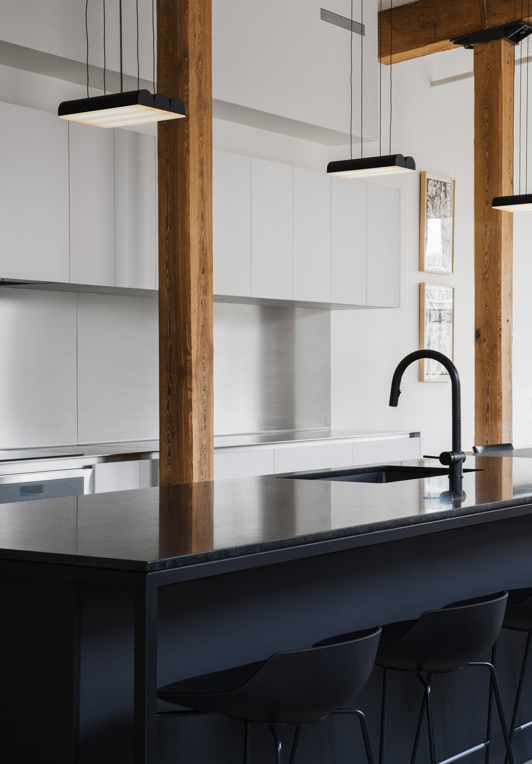 A dream kitchen for food and geology lovers. Labradorite granite, stainless steel, and oak cabinetry hide a coffee nook, laundry, and more in one sculptural volume.
