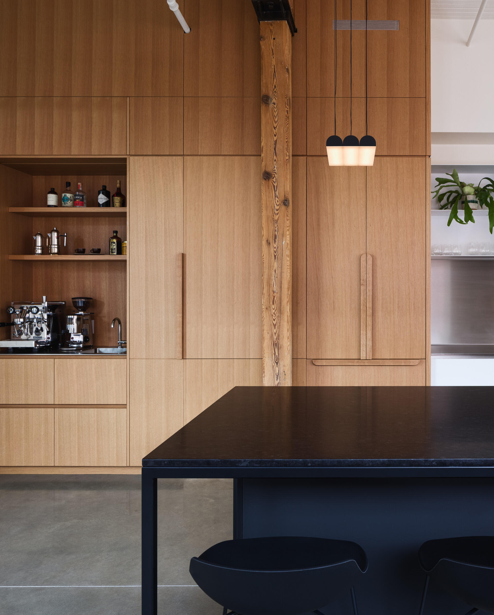 A dream kitchen for food and geology lovers. Labradorite granite, stainless steel, and oak cabinetry hide a coffee nook, laundry, and more in one sculptural volume.