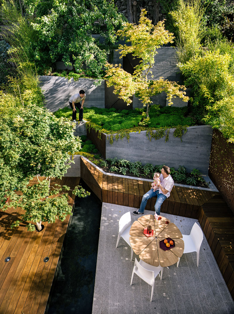 A narrow, sloped backyard is transformed into a Zen-like garden retreat with a winding ramp, concrete terraces, and layered plantings. It also features a reflecting pool, Japanese maples, and panoramic views.