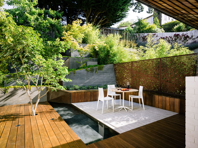 A narrow, sloped backyard is transformed into a Zen-like garden retreat with a winding ramp, concrete terraces, and layered plantings. It also features a reflecting pool, Japanese maples, and panoramic views.