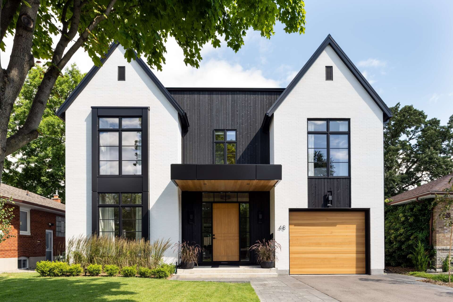 From the street, this home strikes a clear contrast of light and dark. Crisp white brick pairs with matte shou sugi ban siding, while accents of natural cedar soften the composition. This balance of modern and traditional materials introduces the home’s design language, restrained yet welcoming.