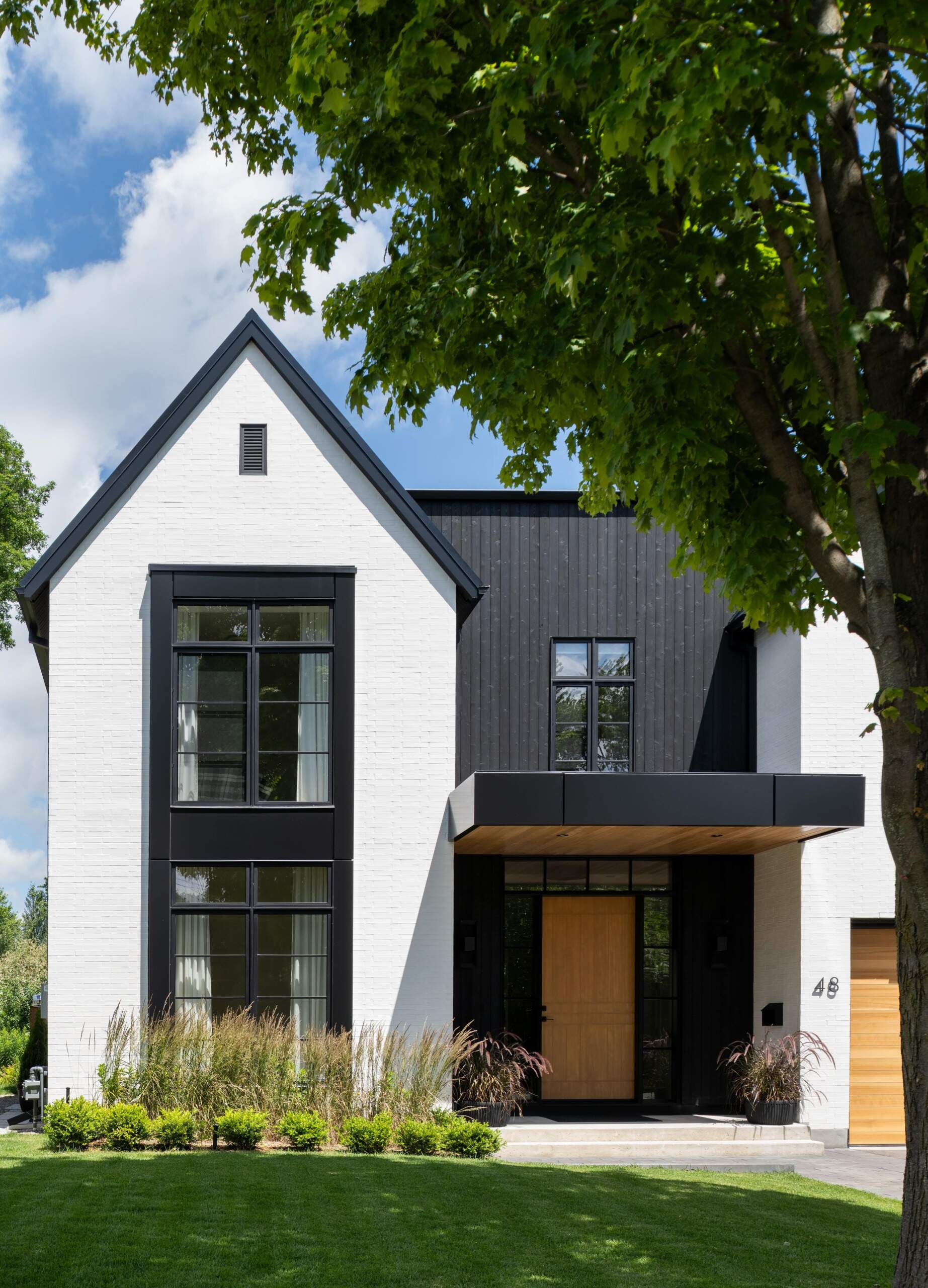 From the street, this home strikes a clear contrast of light and dark. Crisp white brick pairs with matte shou sugi ban siding, while accents of natural cedar soften the composition. This balance of modern and traditional materials introduces the home’s design language, restrained yet welcoming.