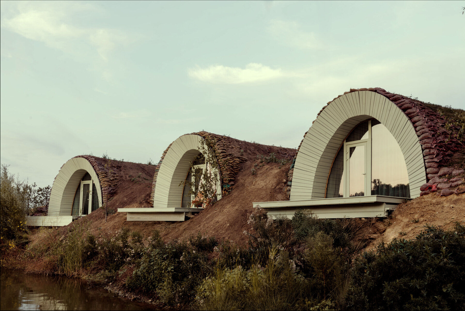 Hobbit-inspired cabins built-into the earth, includes a bedroom, kitchen, and bathroom.