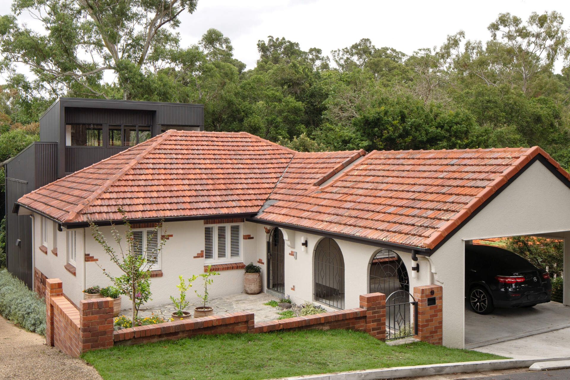 A 1930s bungalow transformed with a steel-framed extension that opens to the treetops, blending recycled timbers, natural stone, and contemporary design.