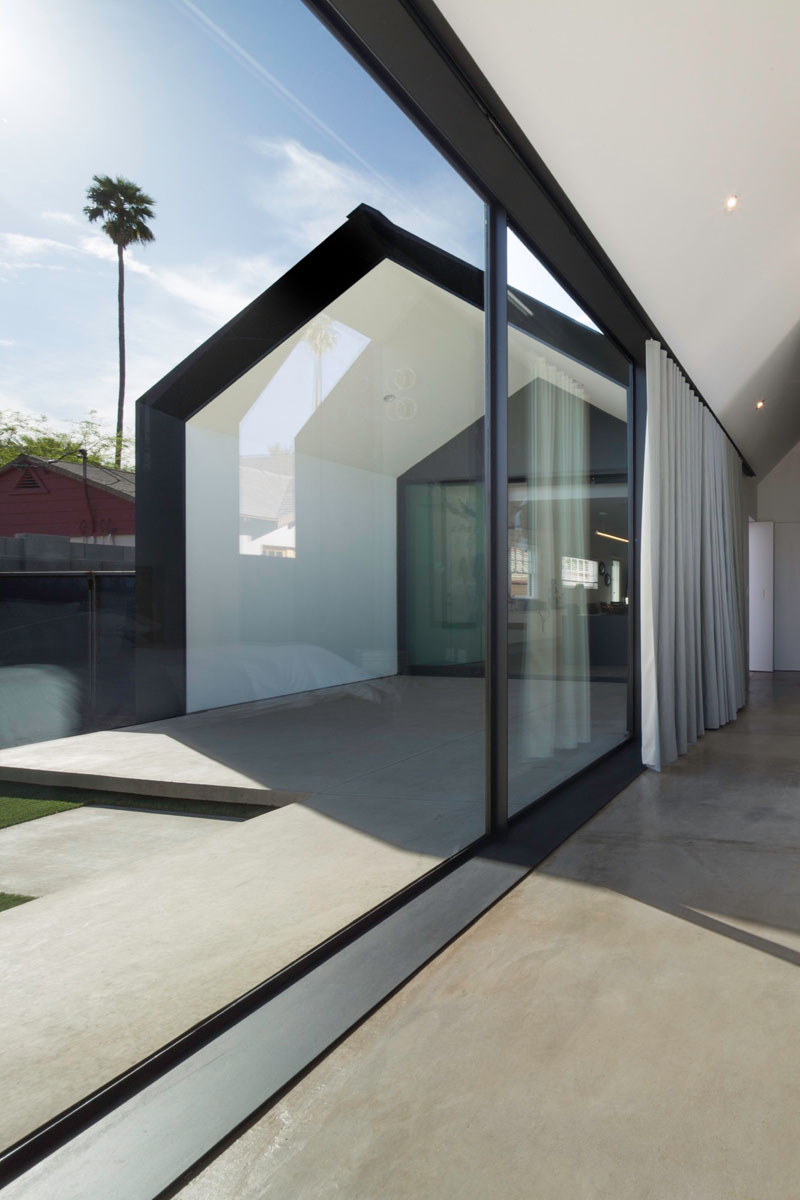 The master suite opens fully to the backyard, with windows that follow the roofline and floor-to-ceiling glass flooding the space with light.