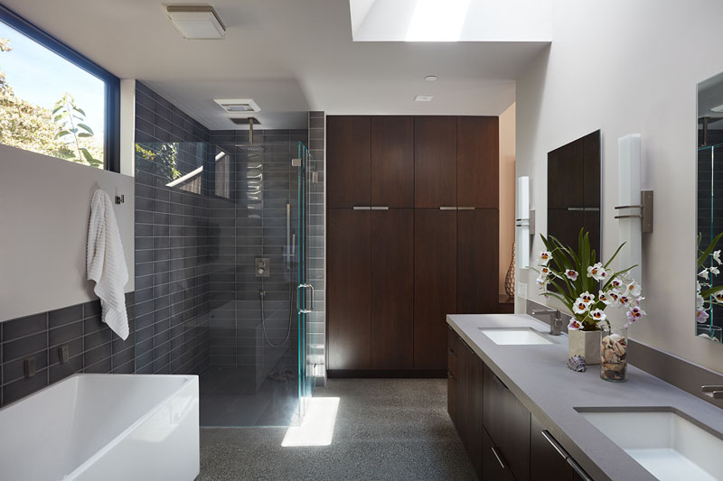 In this primary bathroom, natural light pours in through both a window and a skylight. The shower and bath, though separate, share a unifying wall tile that reinforces the home’s sense of consistency. 