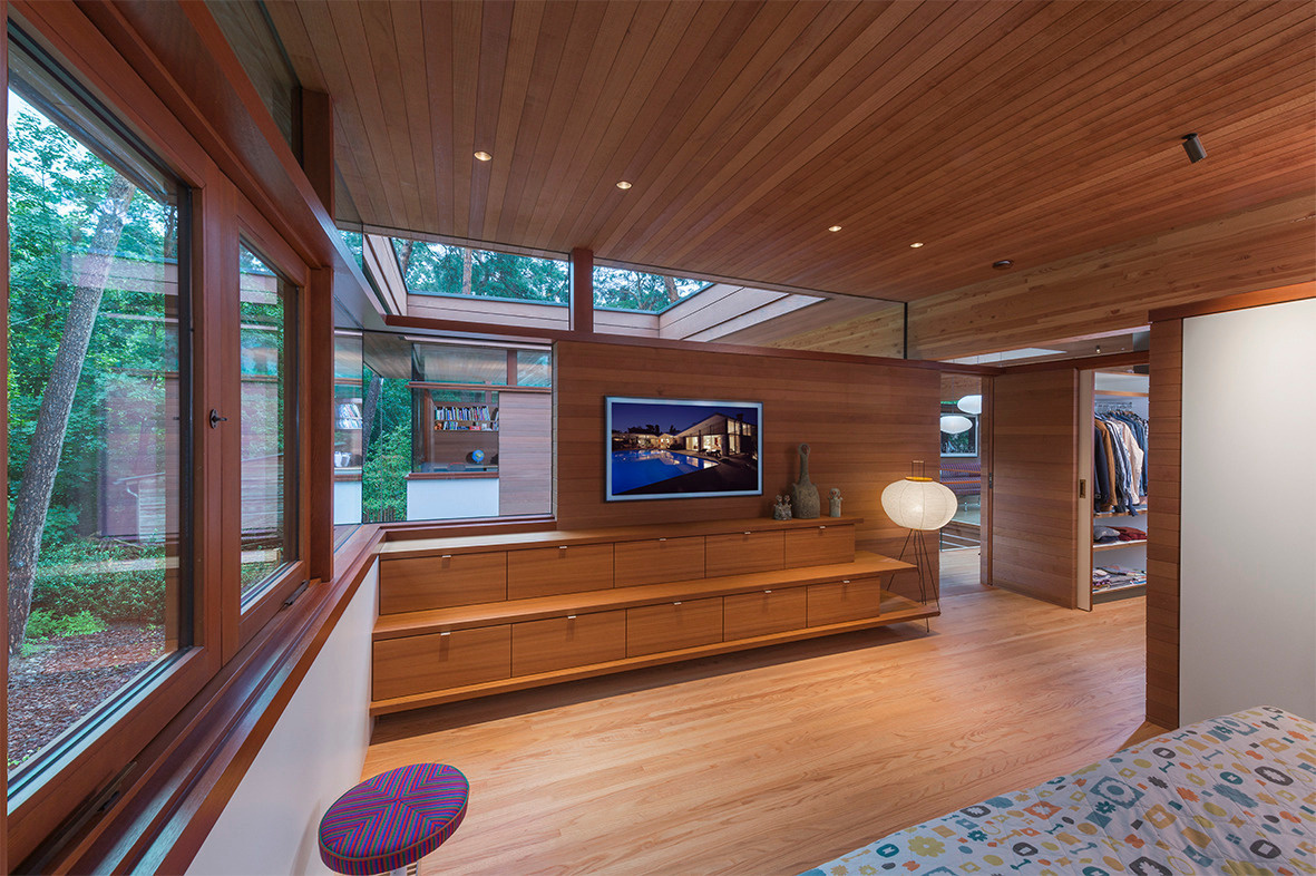 The bedroom carries the same language of openness and nature connection found throughout the house. Large windows frame calming views, while the layout prioritizes comfort, simplicity, and storage.