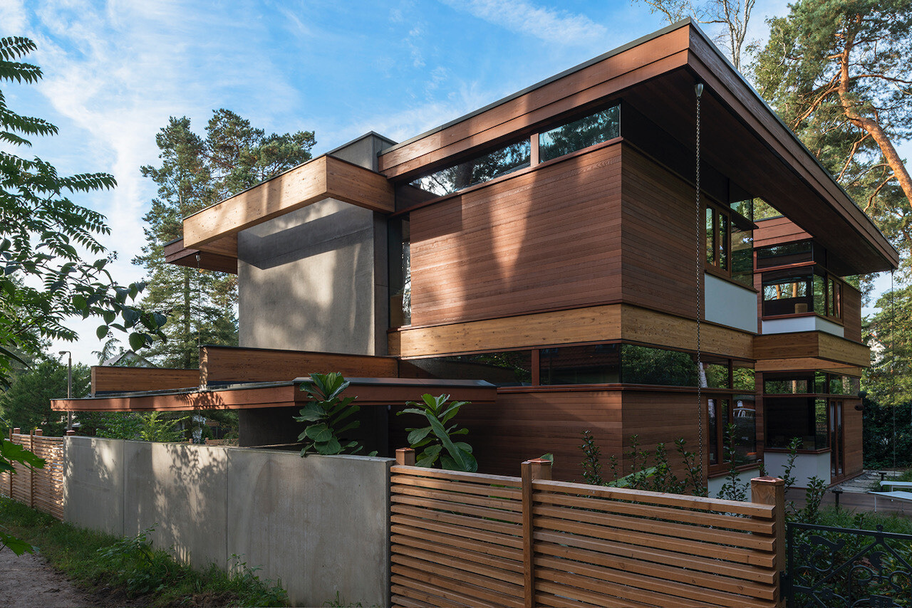 The design of this home includes expansive glass walls that invite the outdoors in, while natural wood tones and warm materials soften the geometry, creating a sense of welcome from the very first glance.