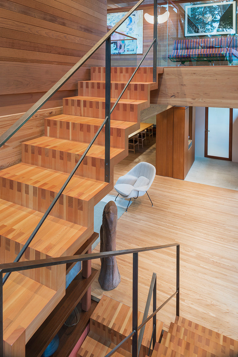 A wood staircase anchors the interior, offering both a practical link between levels and a striking architectural feature.