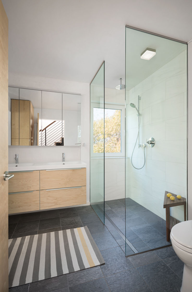 A shower window frames treetop views, turning daily routines into calming moments of connection with nature.
