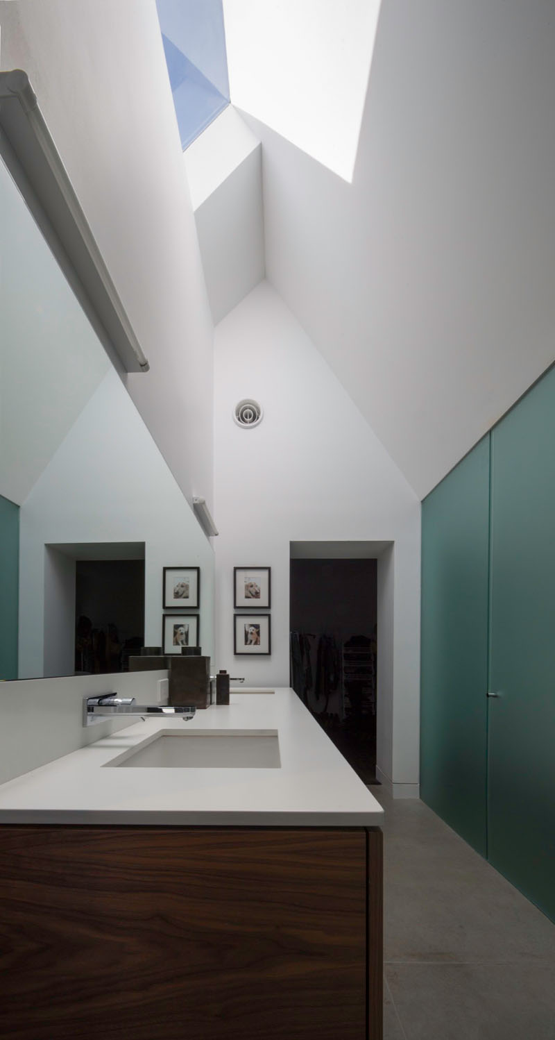 A serene bathroom features a high gabled ceiling and skylight, drawing the eye upward and filling the room with daylight.