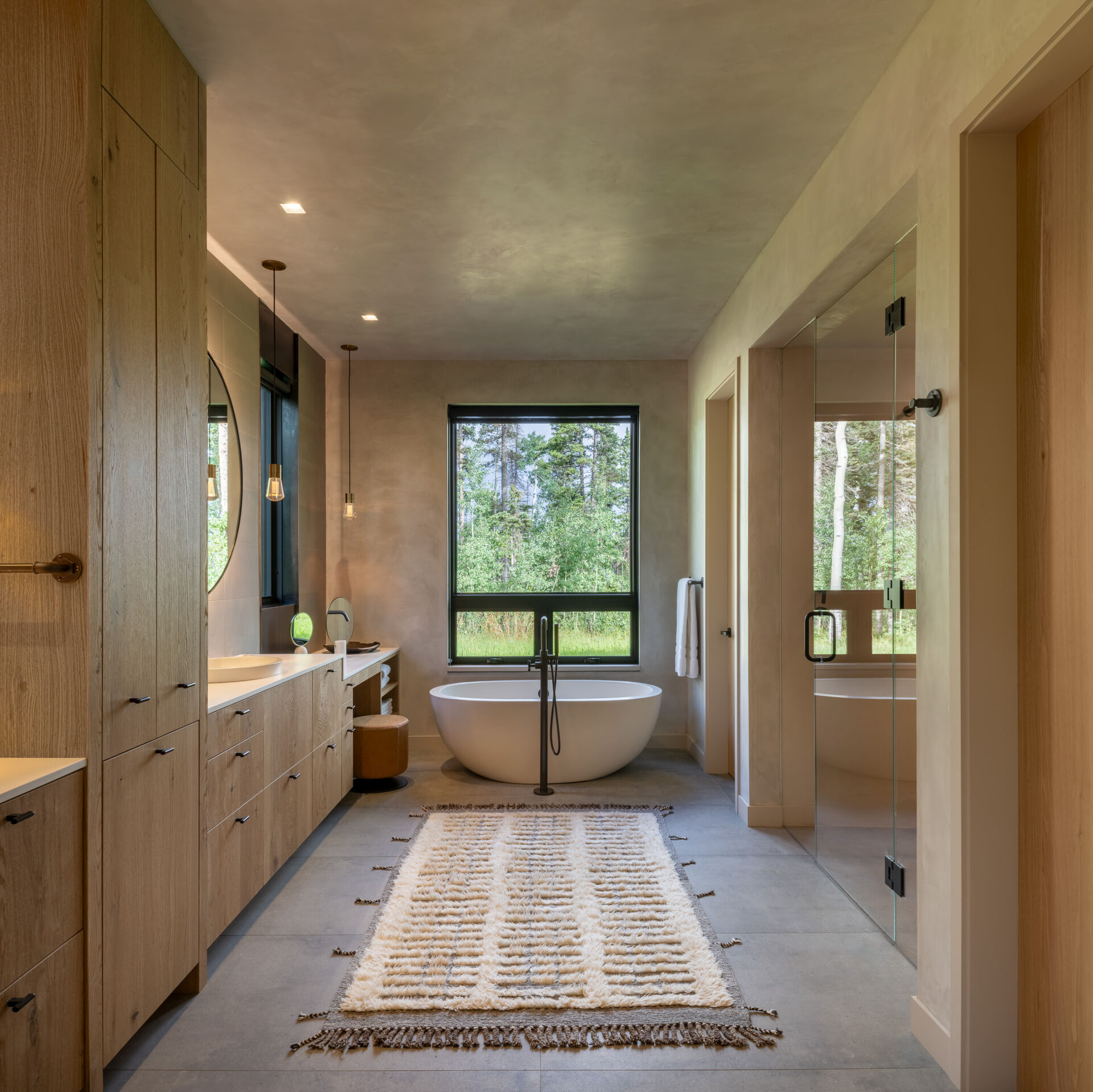 This primary bathroom features a vanity and floor tub that anchor the space, while a glass enclosed shower offers an element of luxury.