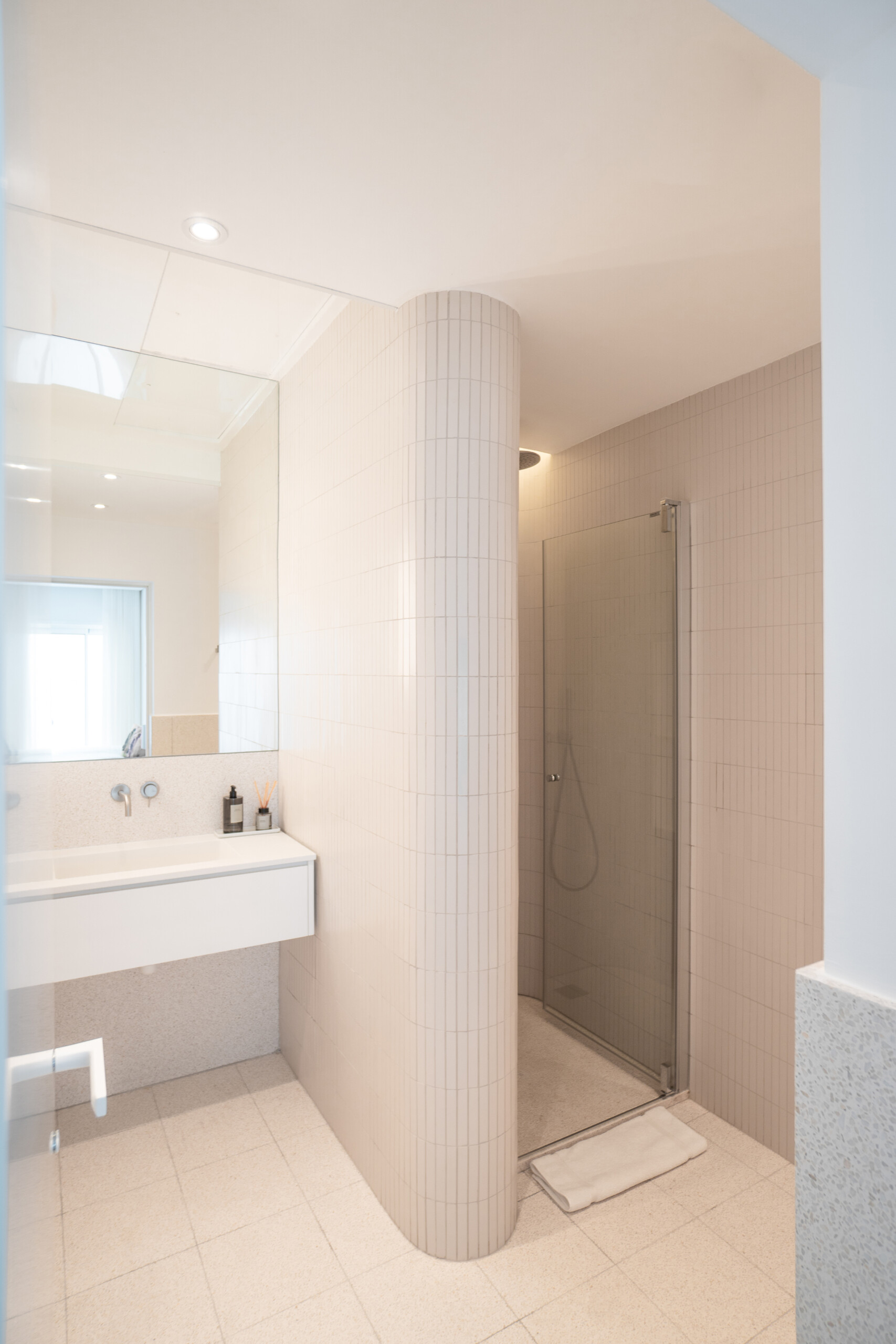 In this bathroom, curves take the lead. Soft-toned materials and indirect lighting work together to highlight the gently rounded walls. A large mirror extends the space visually, while subtle finishes keep the focus on comfort.