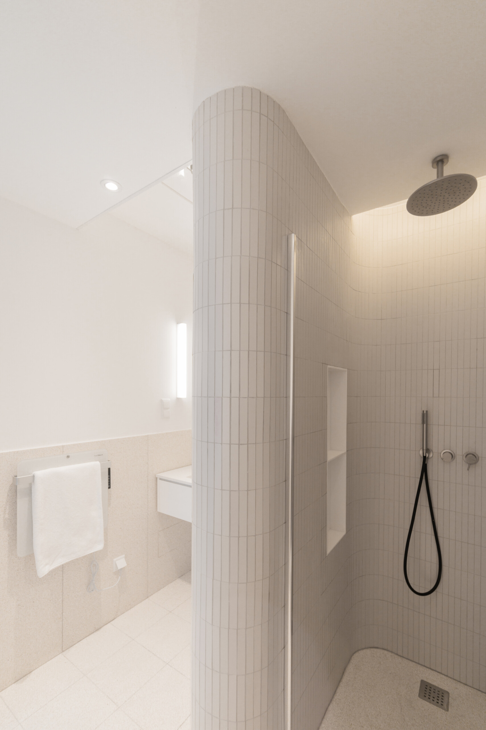 In this bathroom, curves take the lead. Soft-toned materials and indirect lighting work together to highlight the gently rounded walls. A large mirror extends the space visually, while subtle finishes keep the focus on comfort.