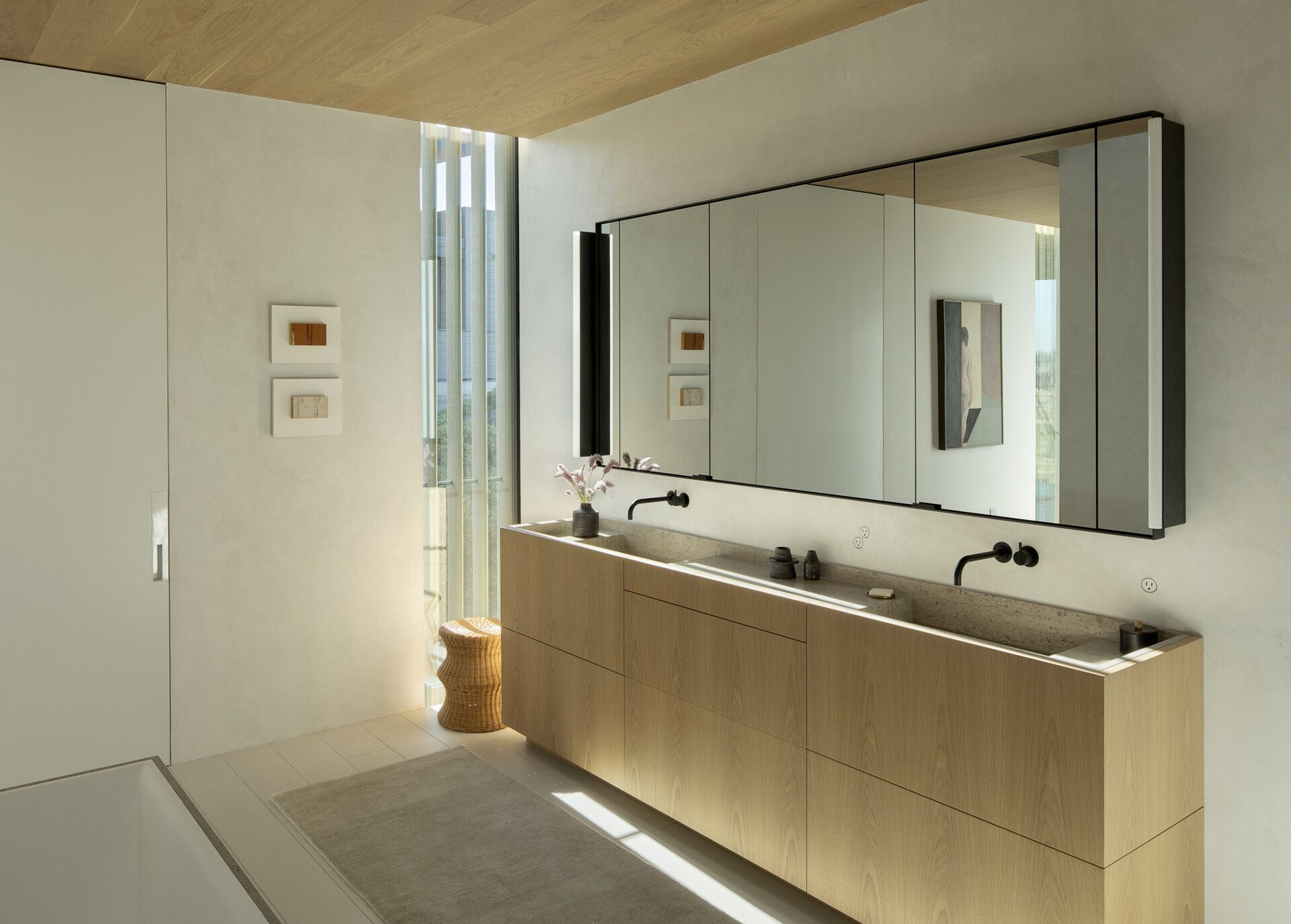 Bathrooms throughout this modern home feature warm wood vanities, adding a natural touch that echoes the exterior cladding and enhances the seamless connection between indoors and out.