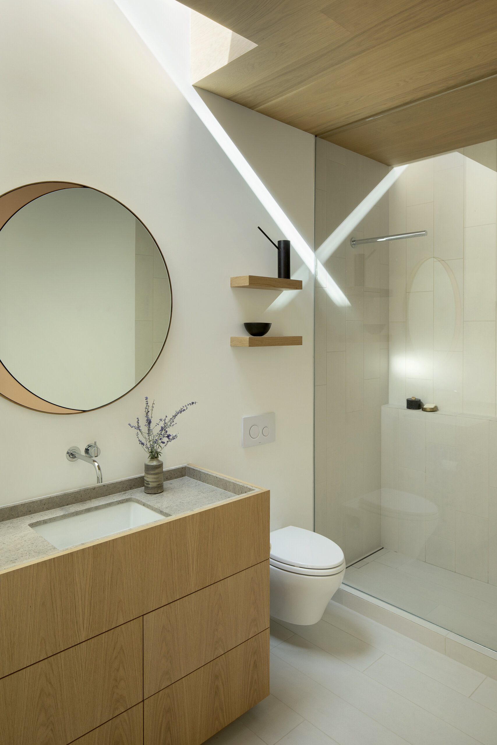 Bathrooms throughout this modern home feature warm wood vanities, adding a natural touch that echoes the exterior cladding and enhances the seamless connection between indoors and out.