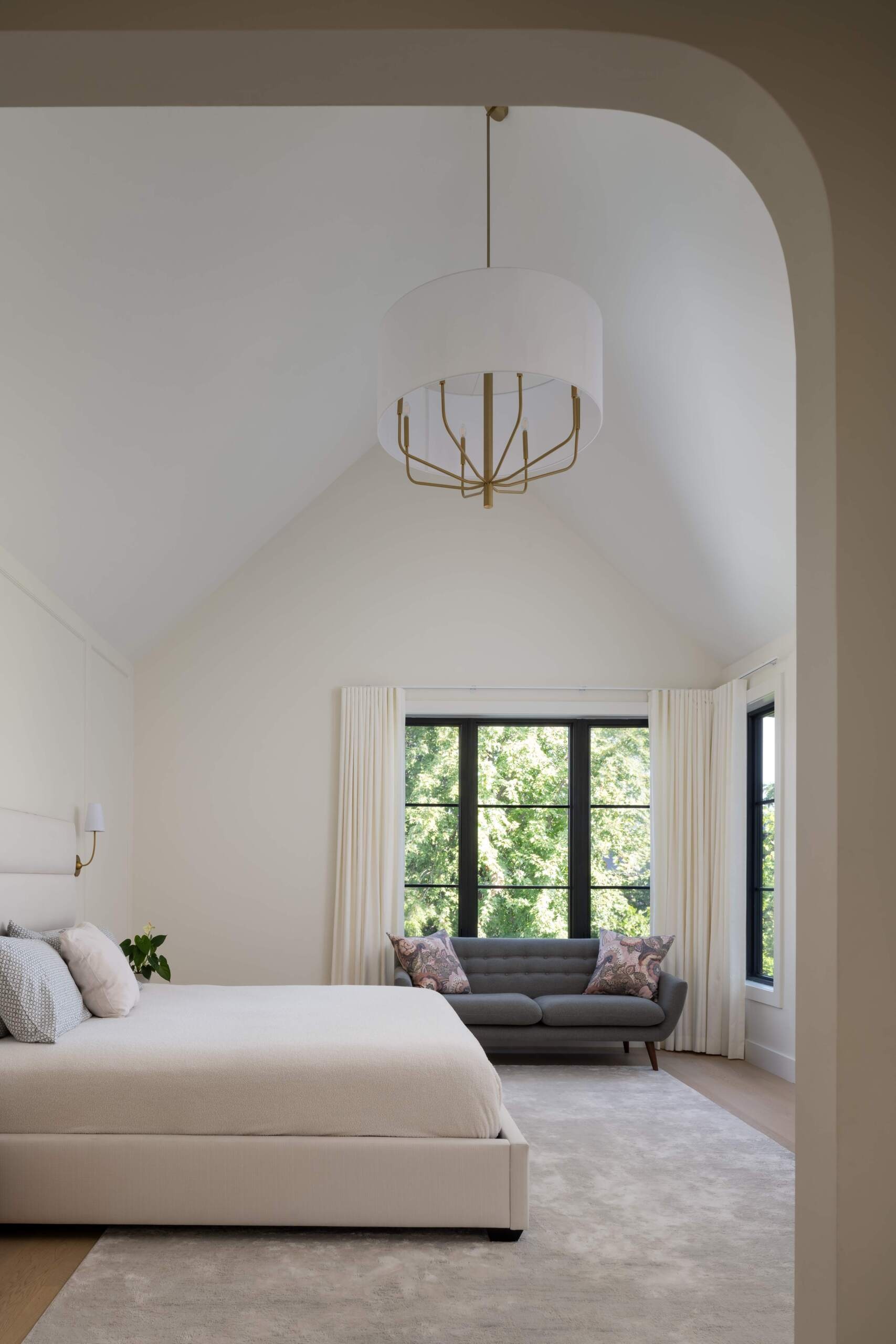 This primary bedroom is elevated with a vaulted ceiling, natural oak flooring, and soft finishes that enhance the sense of ease. Neutral tones create rooms that feel restful and enduring.