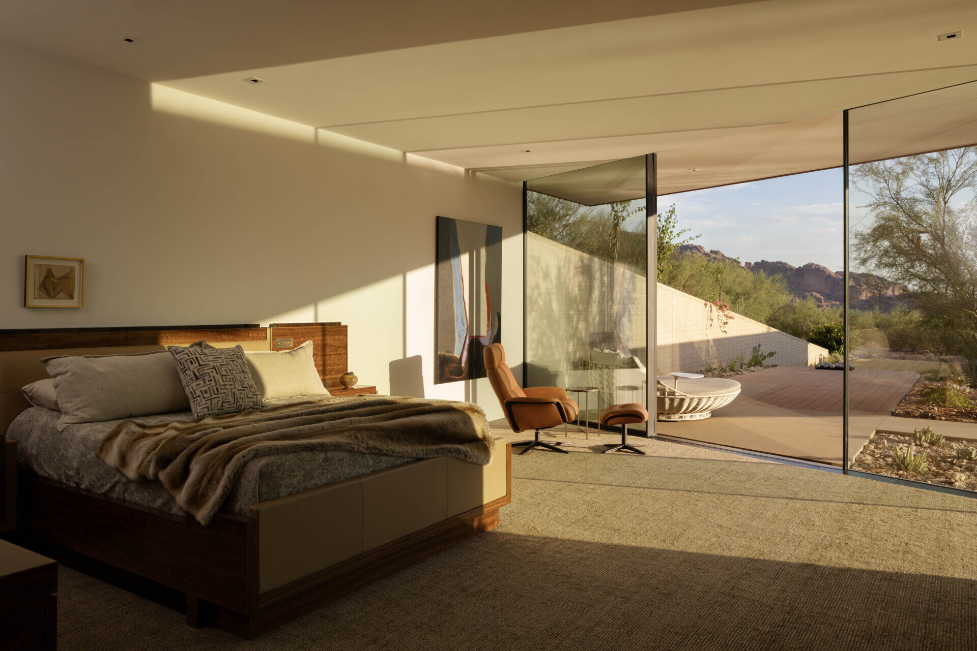 This bedroom embraces a serene, private atmosphere, with large windows framing the desert landscape. Soft materials and muted tones create a calming retreat within the home’s protective shell.