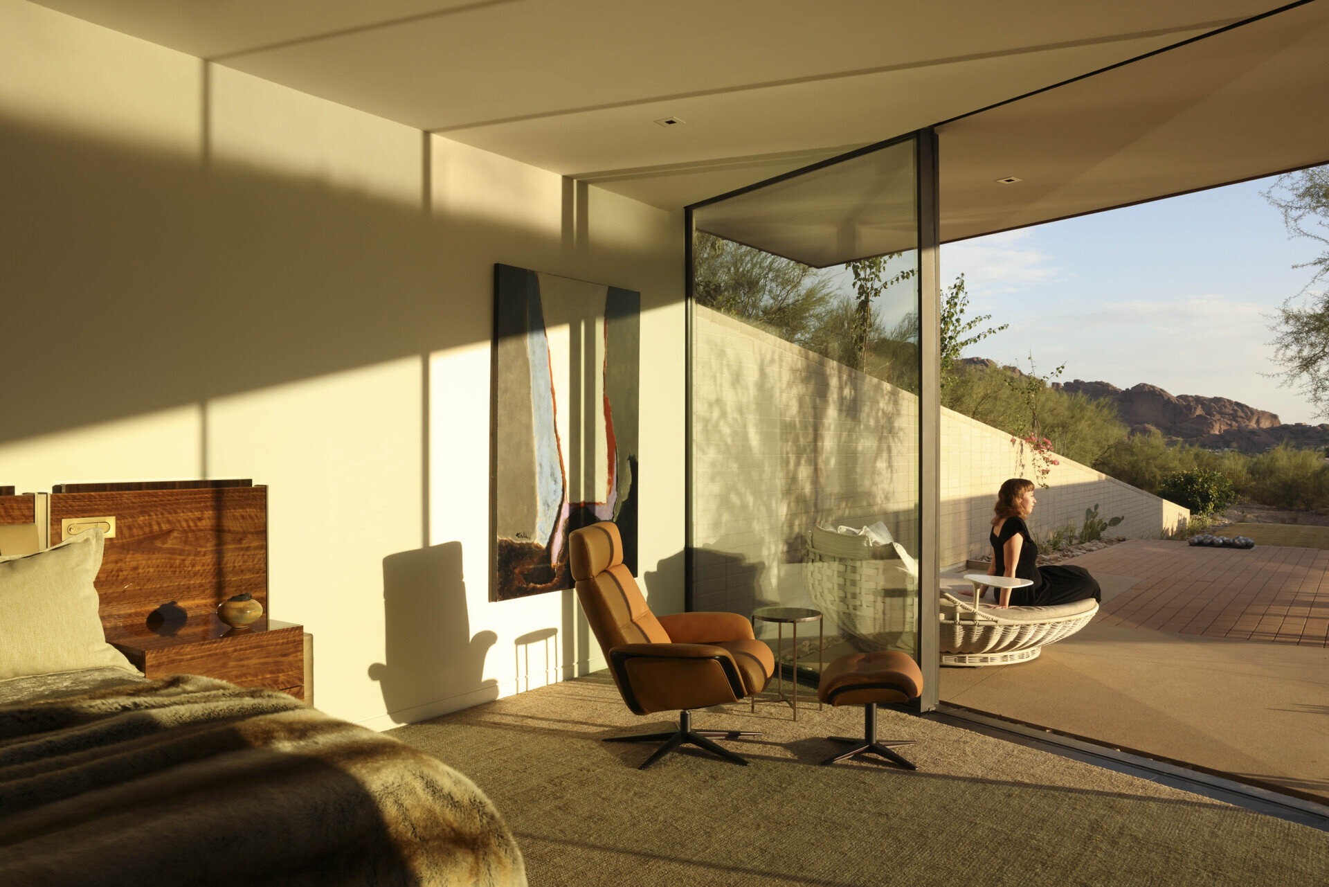 This bedroom embraces a serene, private atmosphere, with large windows framing the desert landscape. Soft materials and muted tones create a calming retreat within the home’s protective shell.