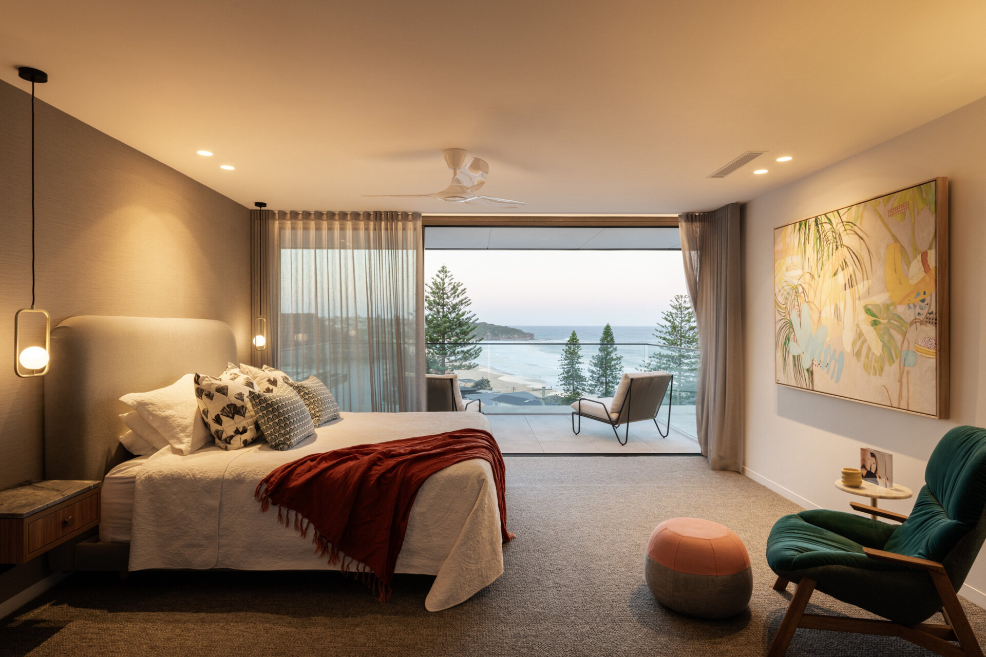This primary bedroom enjoys a private balcony that captures an elevated view over Curl Curl beach, secluded yet still connected to the ever-present beachscape.