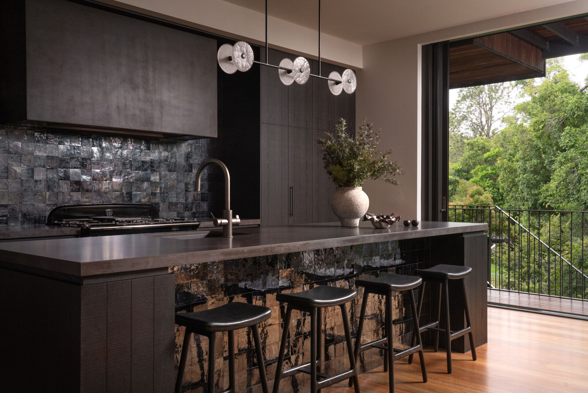 A moody, textured kitchen with custom timber joinery, handmade tiles, and a statement island, paired with a discreet butler’s pantry for effortless entertaining.