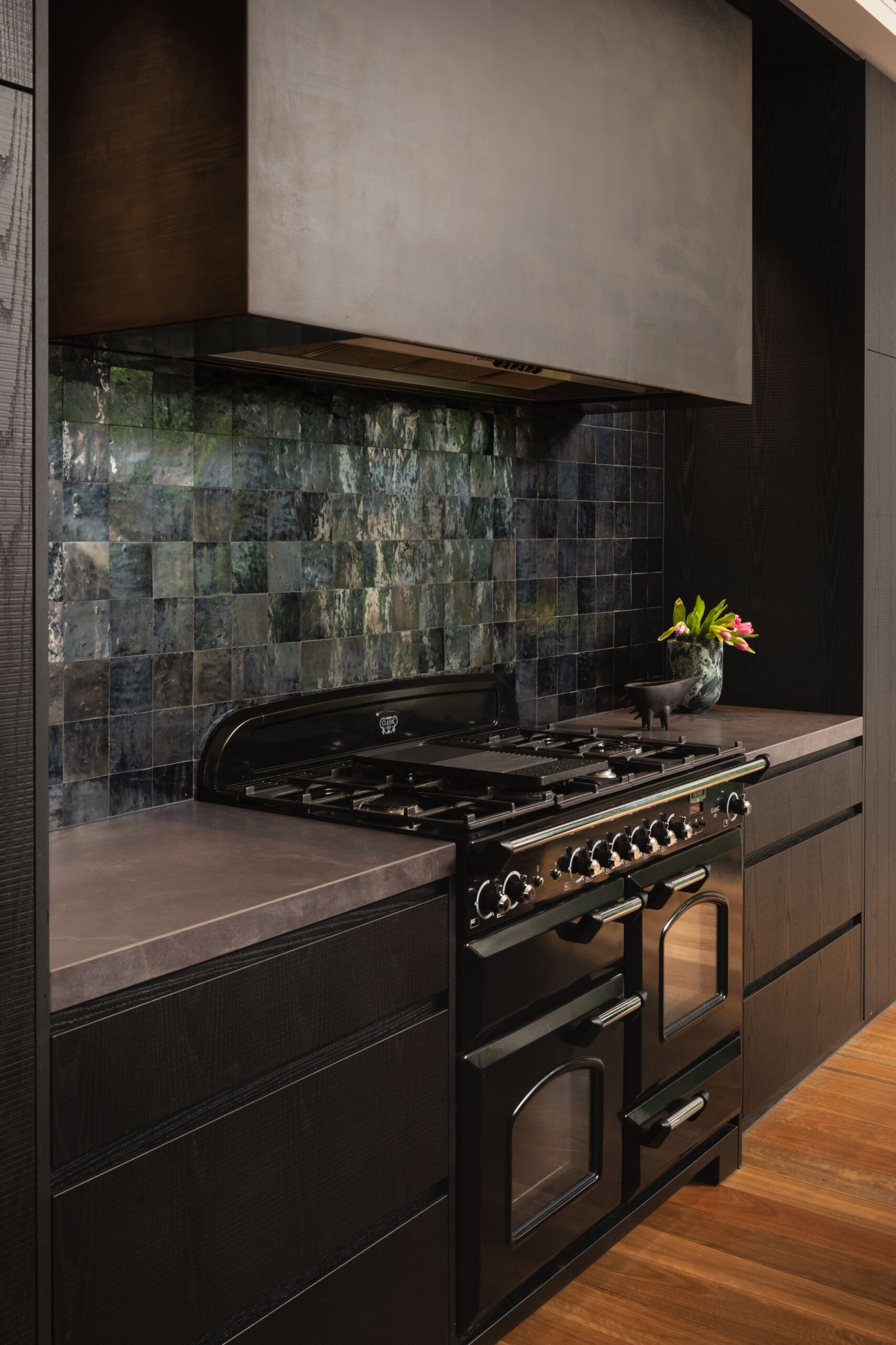 A moody, textured kitchen with custom timber joinery, handmade tiles, and a statement island, paired with a discreet butler’s pantry for effortless entertaining.