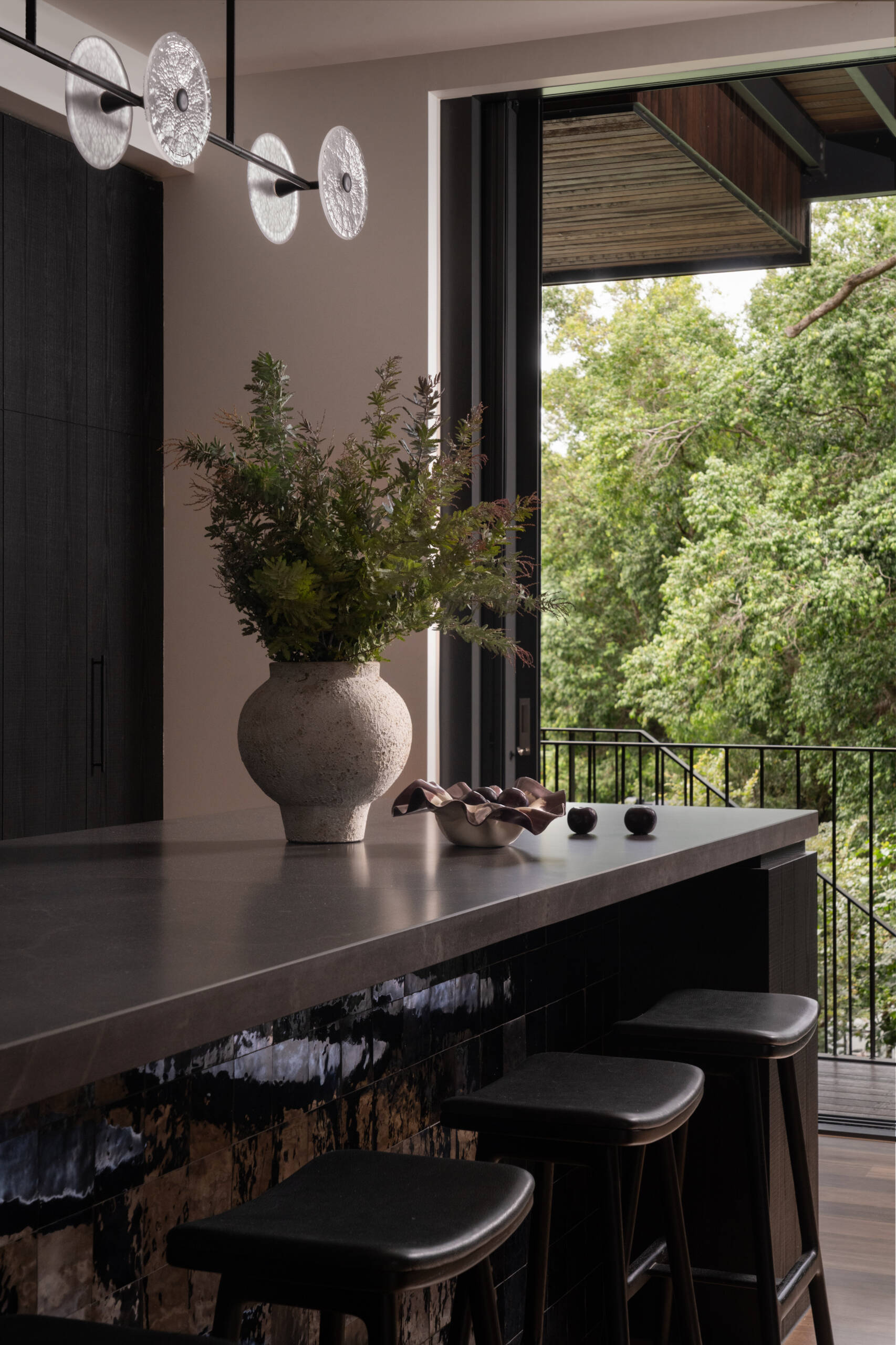 A moody, textured kitchen with custom timber joinery, handmade tiles, and a statement island, paired with a discreet butler’s pantry for effortless entertaining.