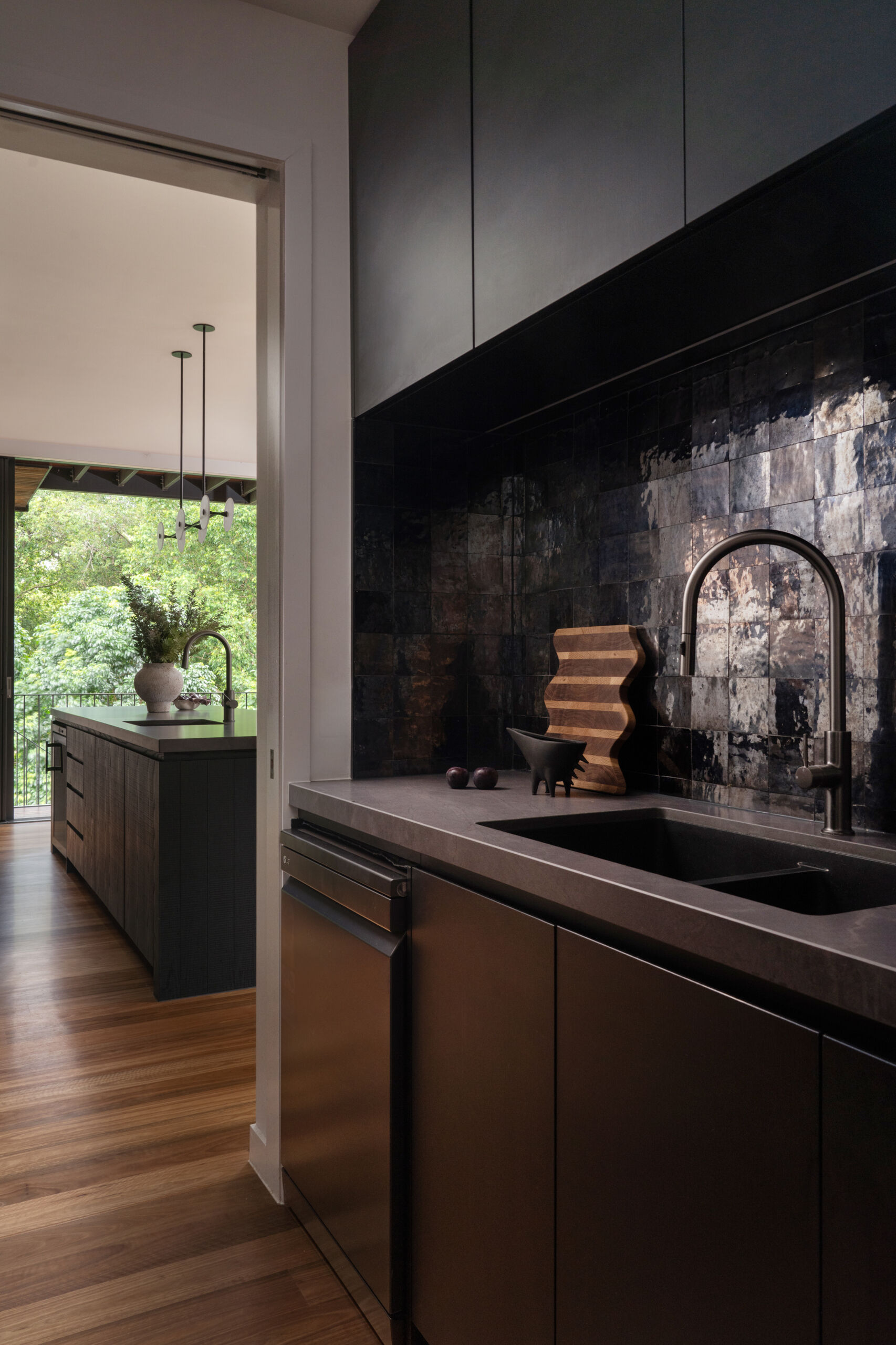 A moody, textured kitchen with custom timber joinery, handmade tiles, and a statement island, paired with a discreet butler’s pantry for effortless entertaining.