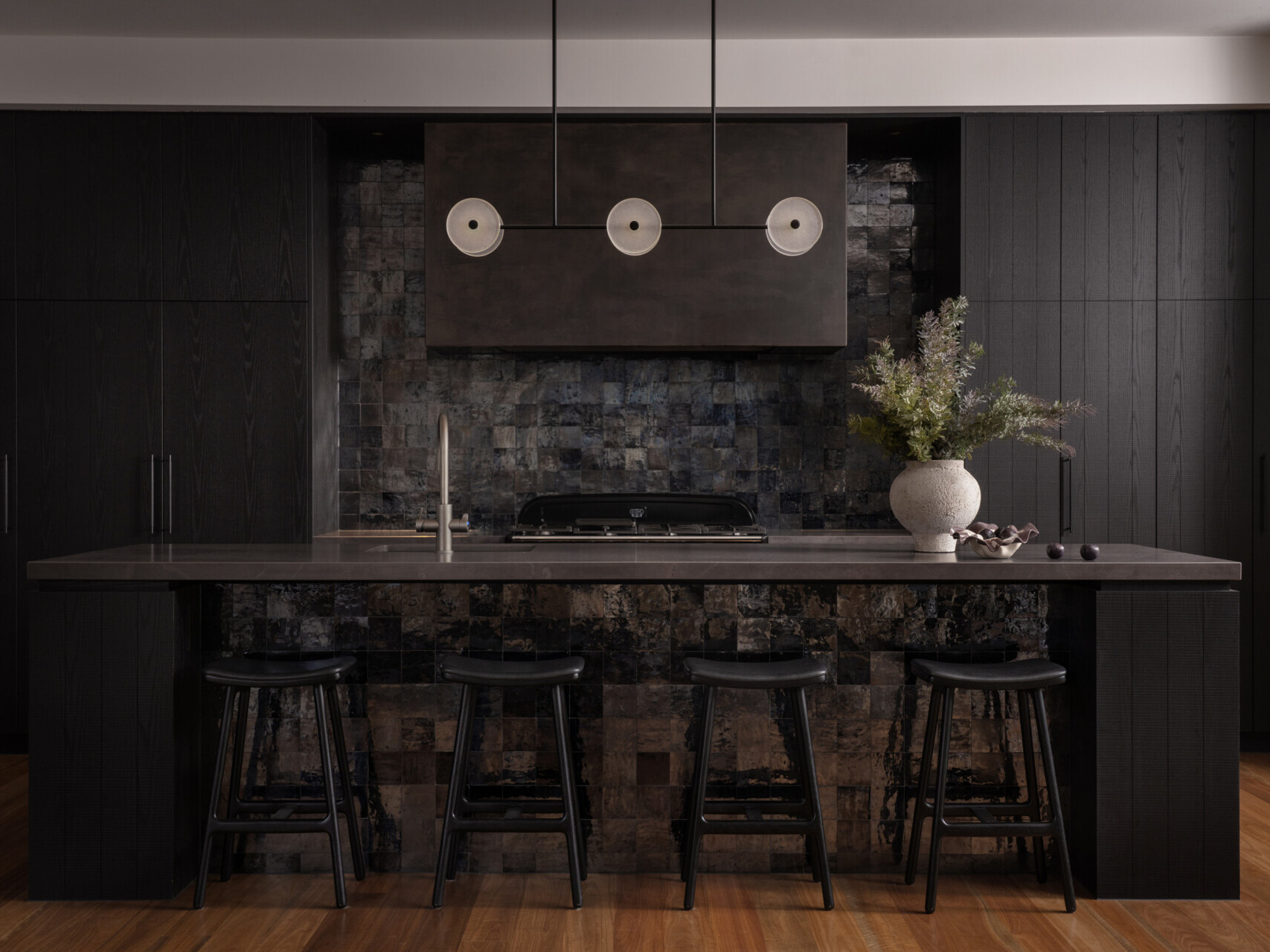 A moody, textured kitchen with custom timber joinery, handmade tiles, and a statement island, paired with a discreet butler’s pantry for effortless entertaining.