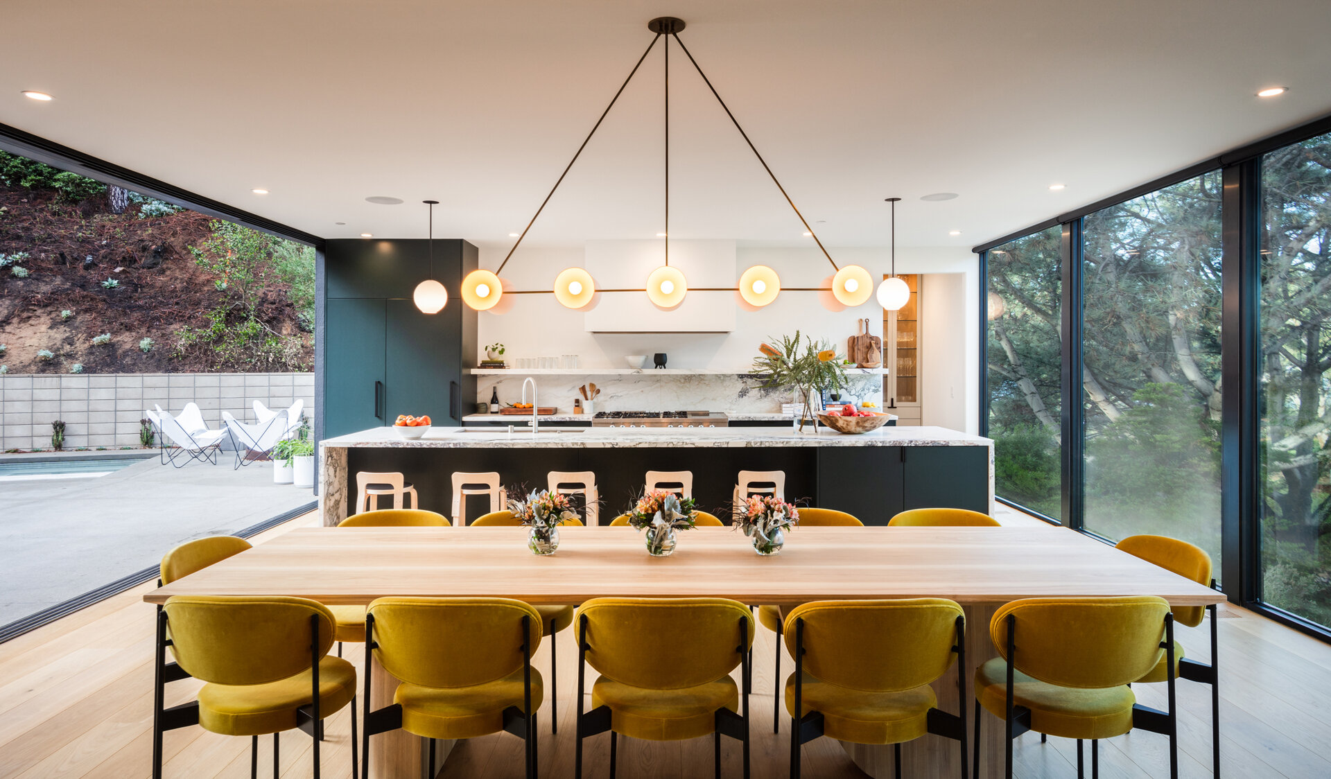 Positioned to enjoy tree-filled views, the dining area flows effortlessly between kitchen and living spaces. Natural light fills the room, creating a warm setting for daily meals or larger celebrations.
