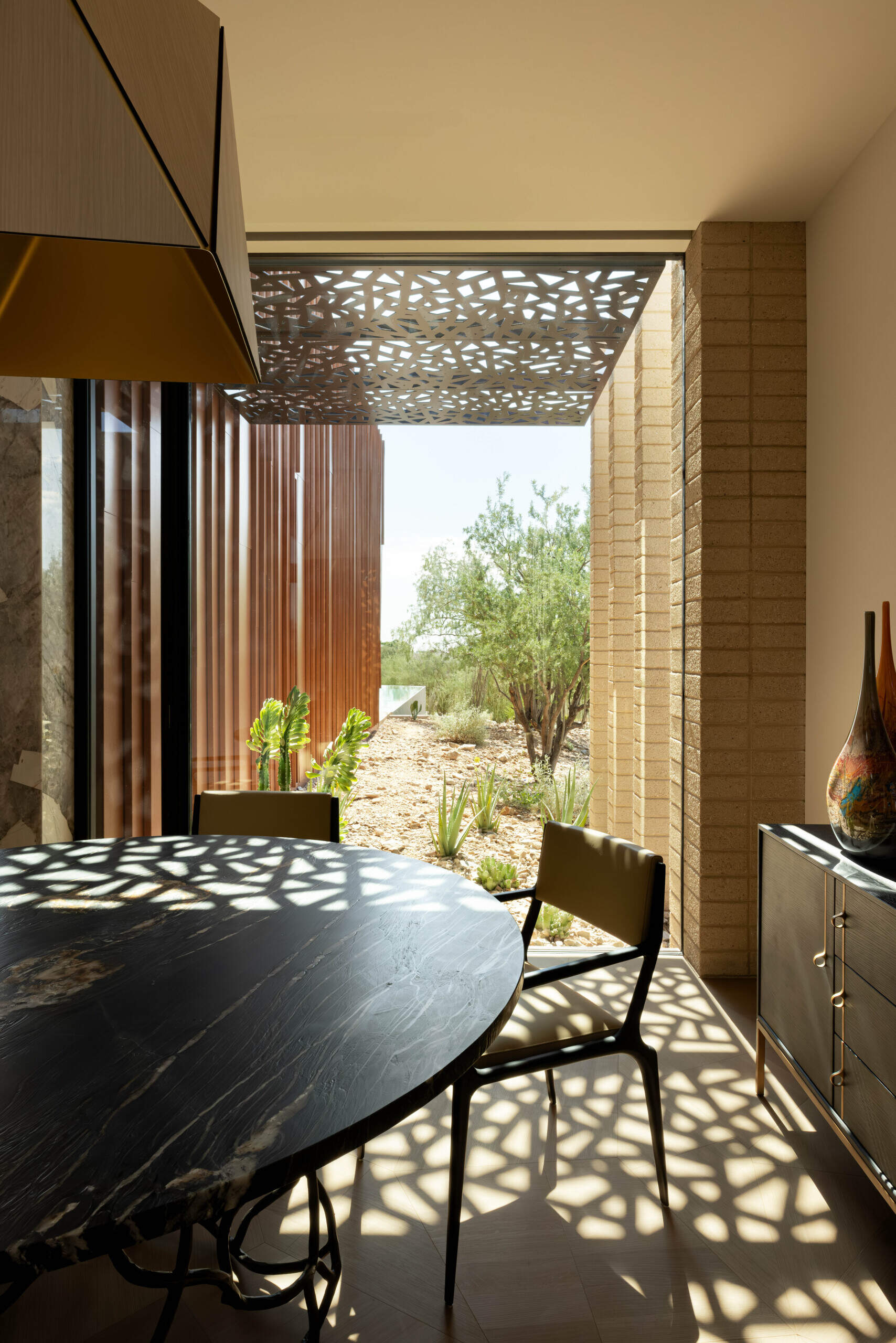 Intimate dining areas are strategically placed to connect with both indoor and outdoor environments. The interplay of light through patterned screens adds texture to mealtime settings.