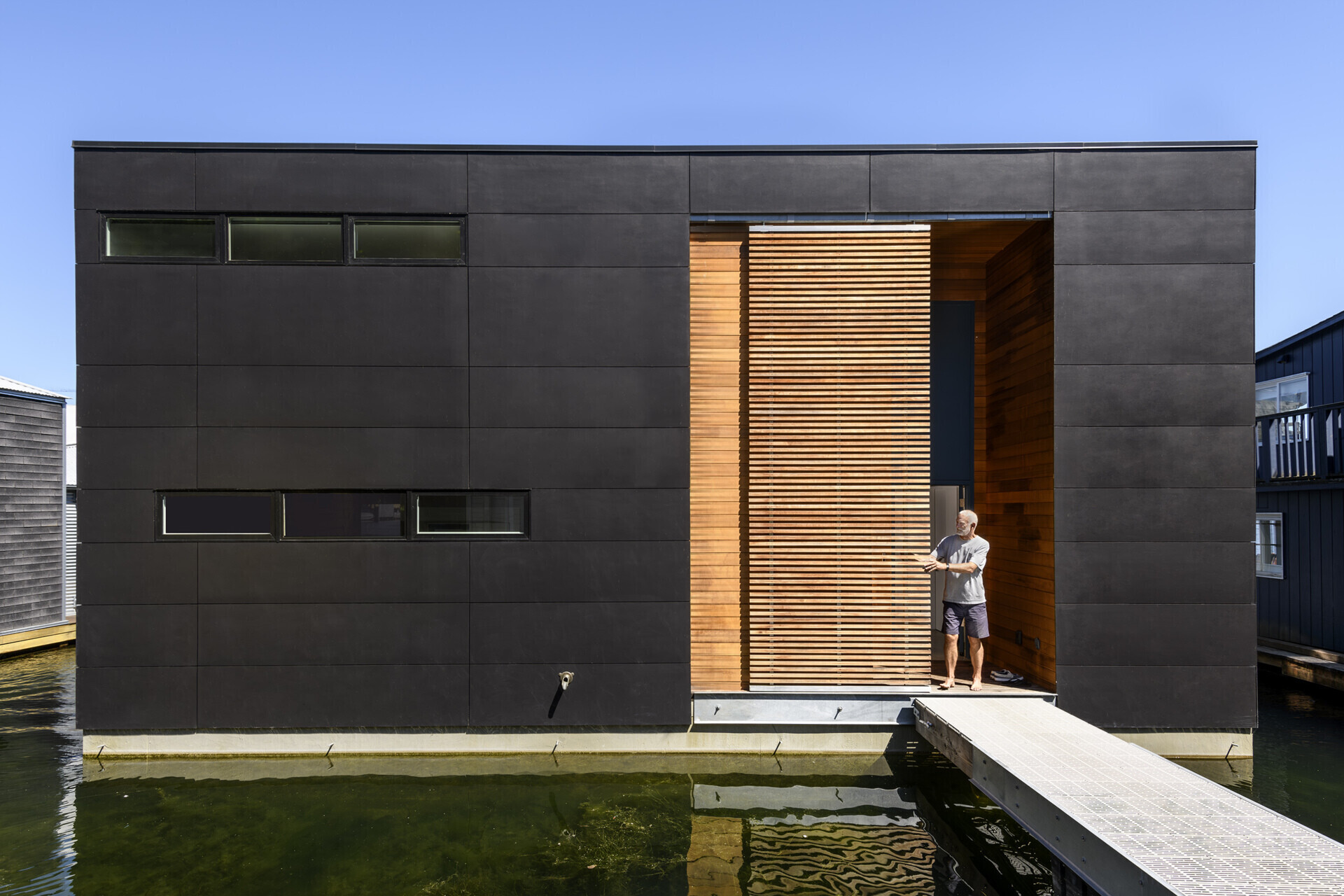The oversized sliding wood screen on this float home gives them control over light, privacy, and transparency, enhancing the home’s adaptable character.