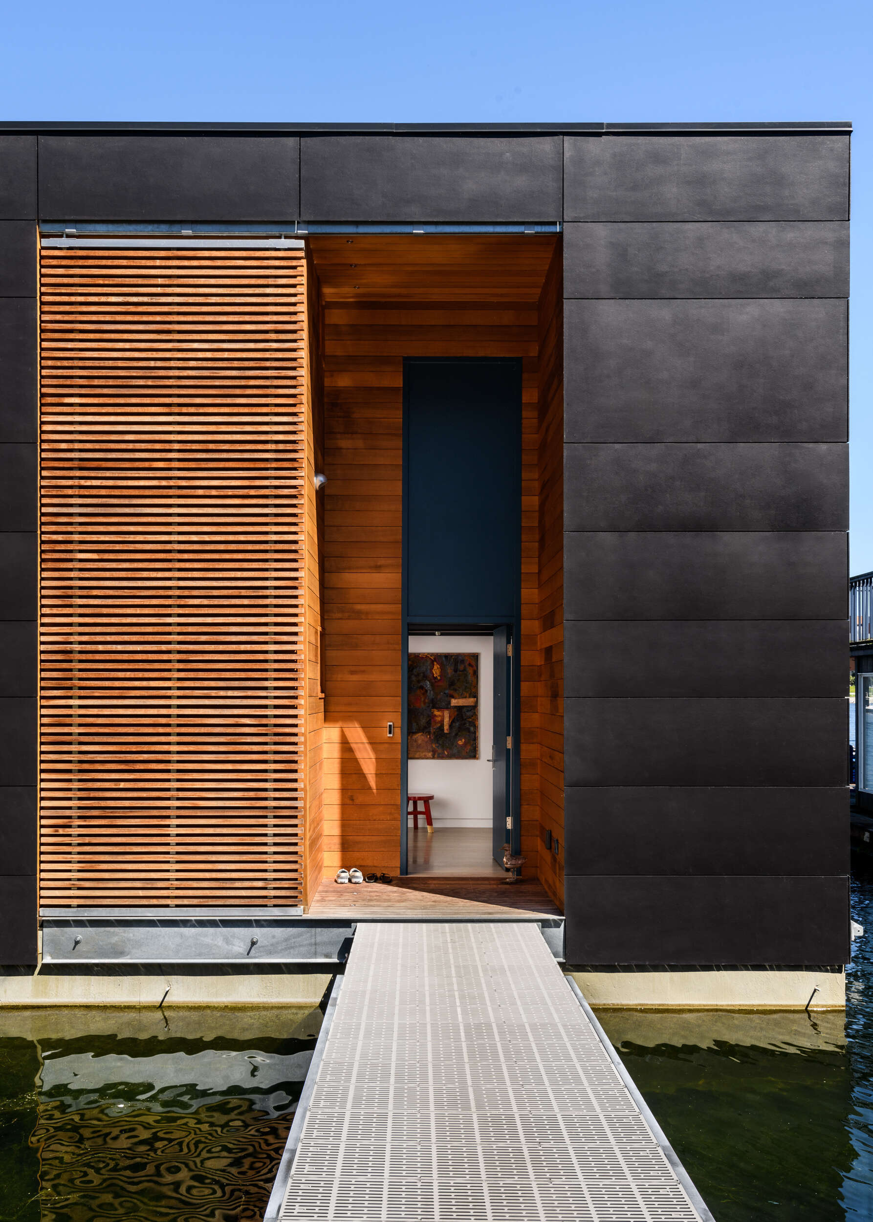 The oversized sliding wood screen on this float home gives them control over light, privacy, and transparency, enhancing the home’s adaptable character.