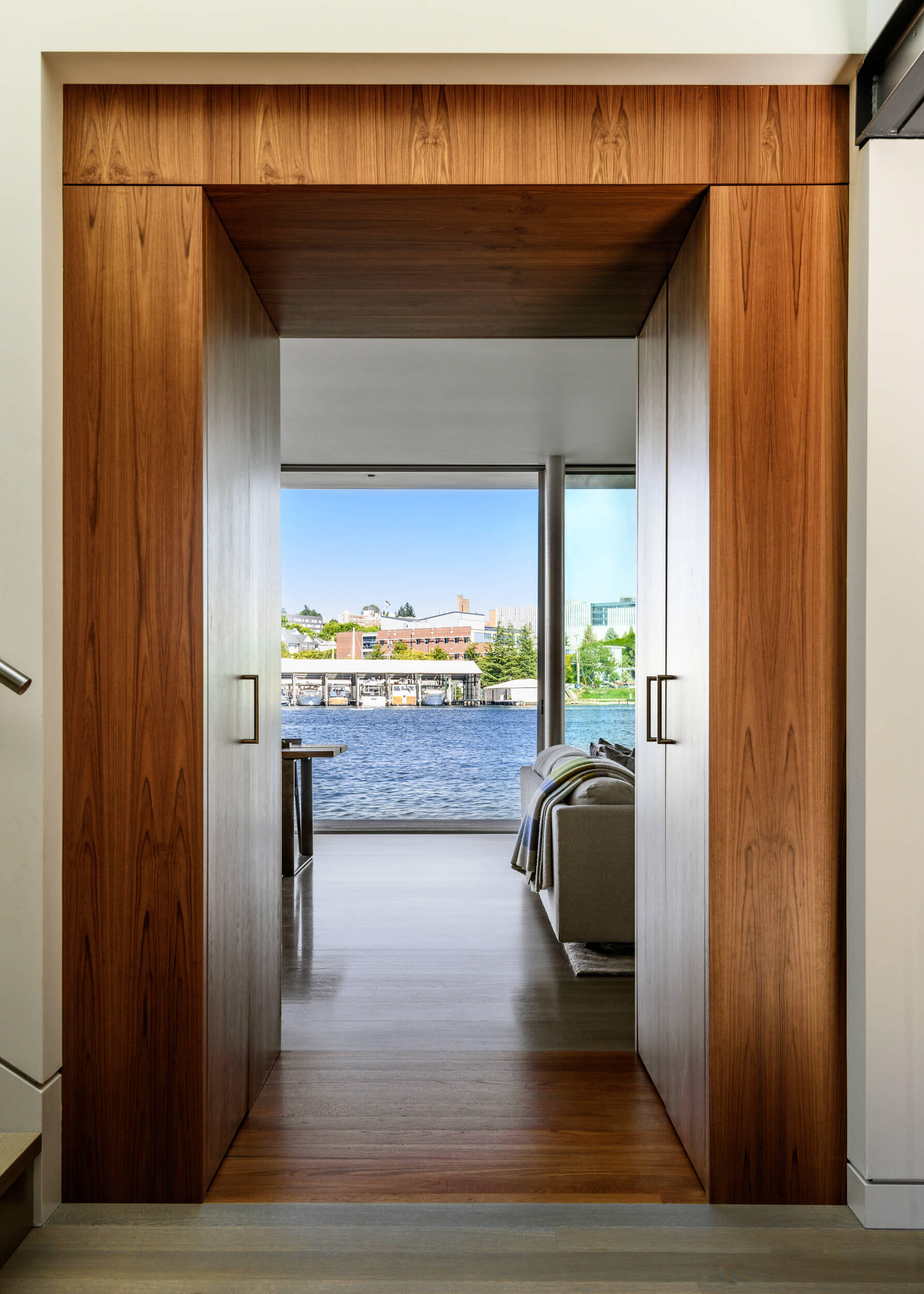 Inside this float home, the material palette stays warm and consistent. White oak flooring runs throughout, while teak cabinetry and accents draw inspiration from the boating community.