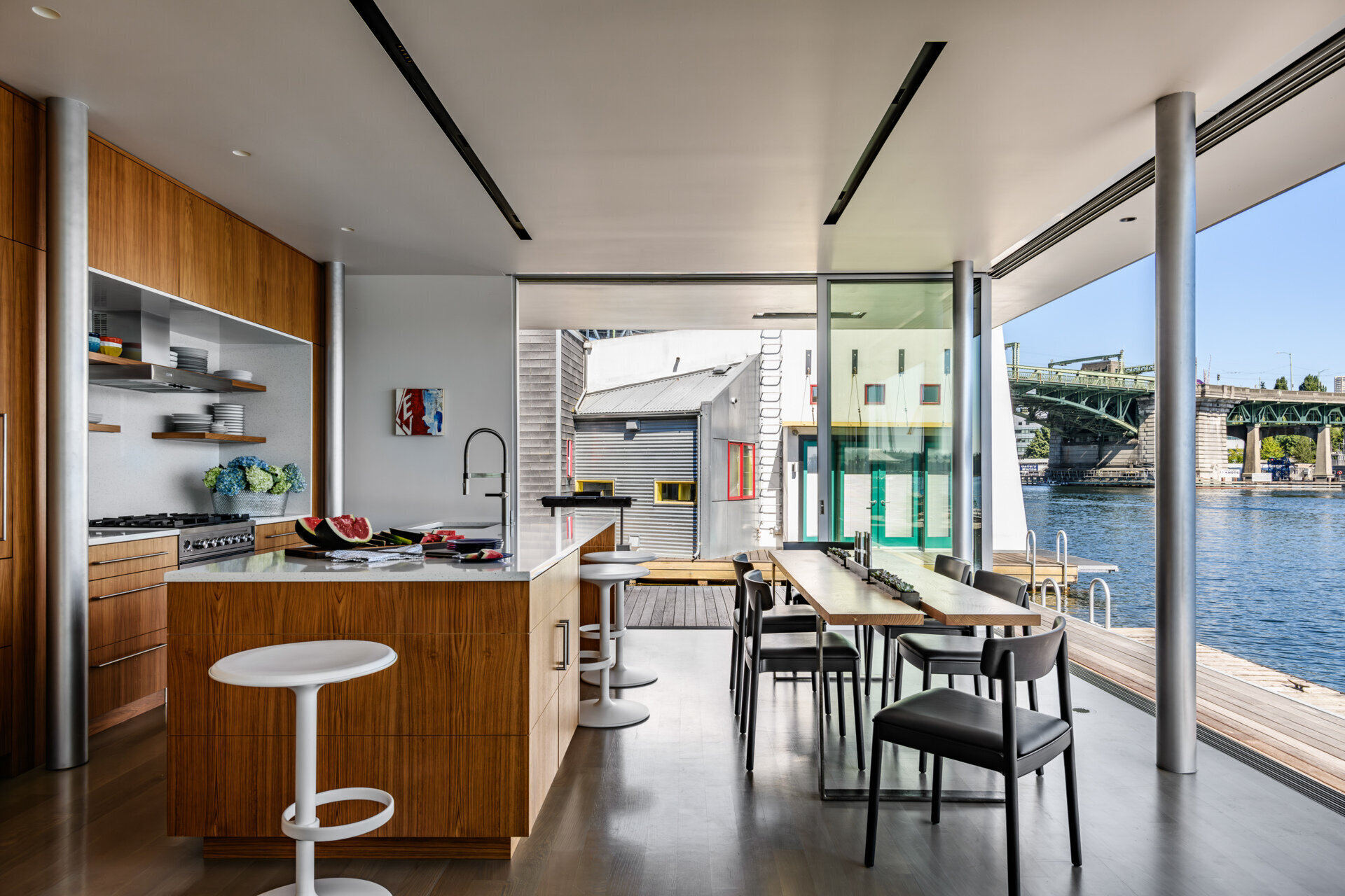 This cabinetry in the living room that lines the wall transitions to become the kitchen cabinets, while the dining area sits seamlessly between the kitchen island and the deck.