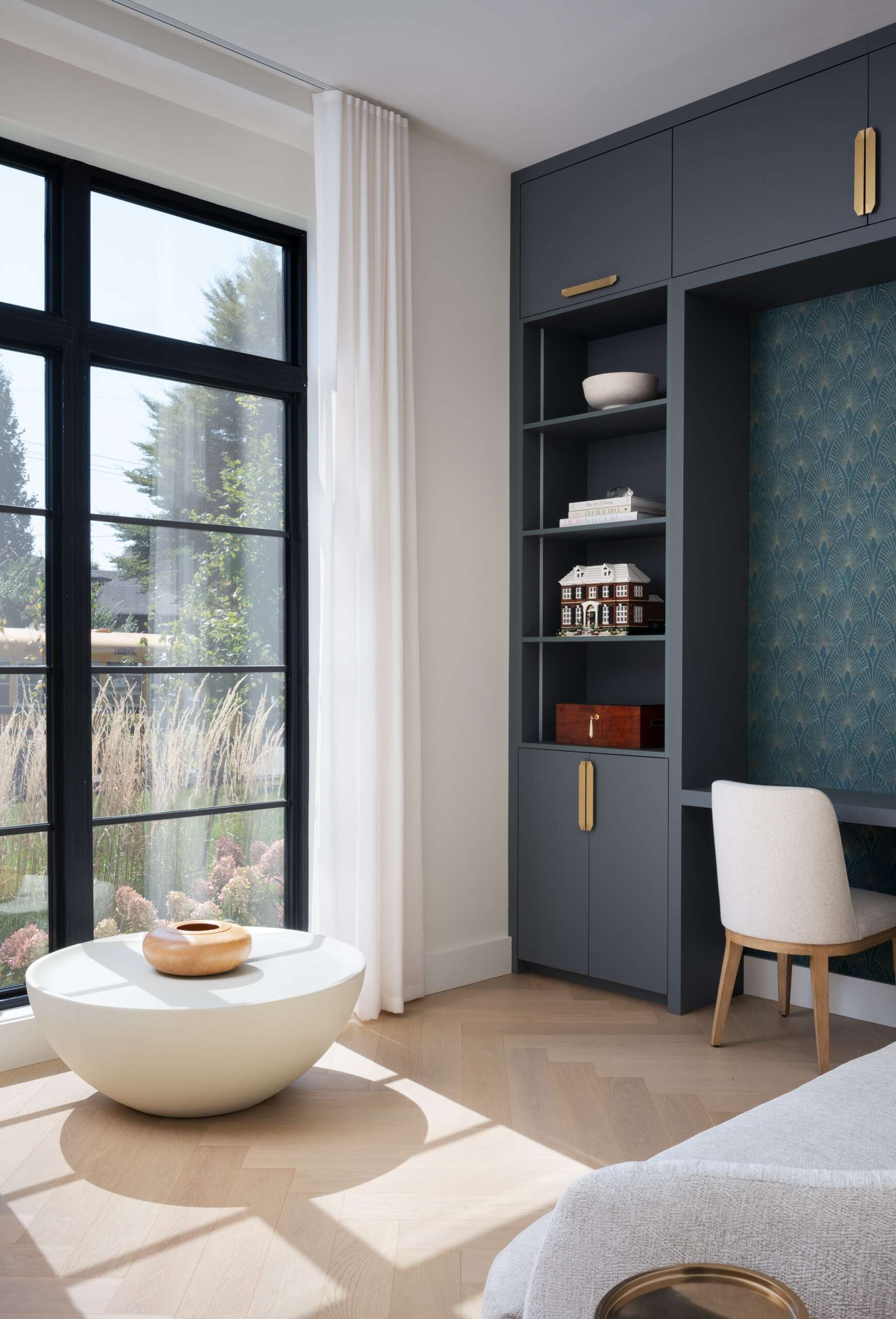 This home office, with a wall of built-in cabinetry, shelving, and a desk, provides a quiet zone for focus and productivity, continuing the balance of function and calm found throughout.
