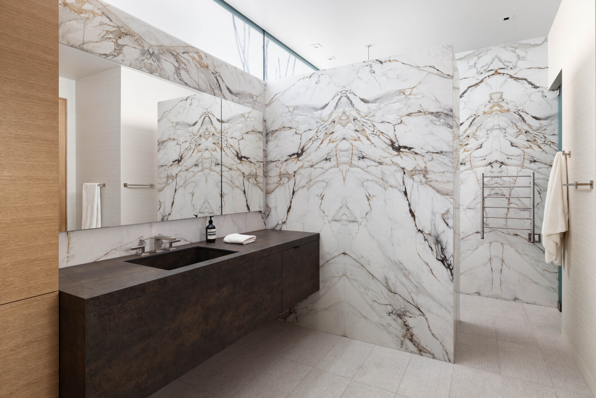 This bathroom blends luxury with nature, using stone and glass to bring in natural light while maintaining privacy. Clean lines and organic textures mirror the home’s overall aesthetic.