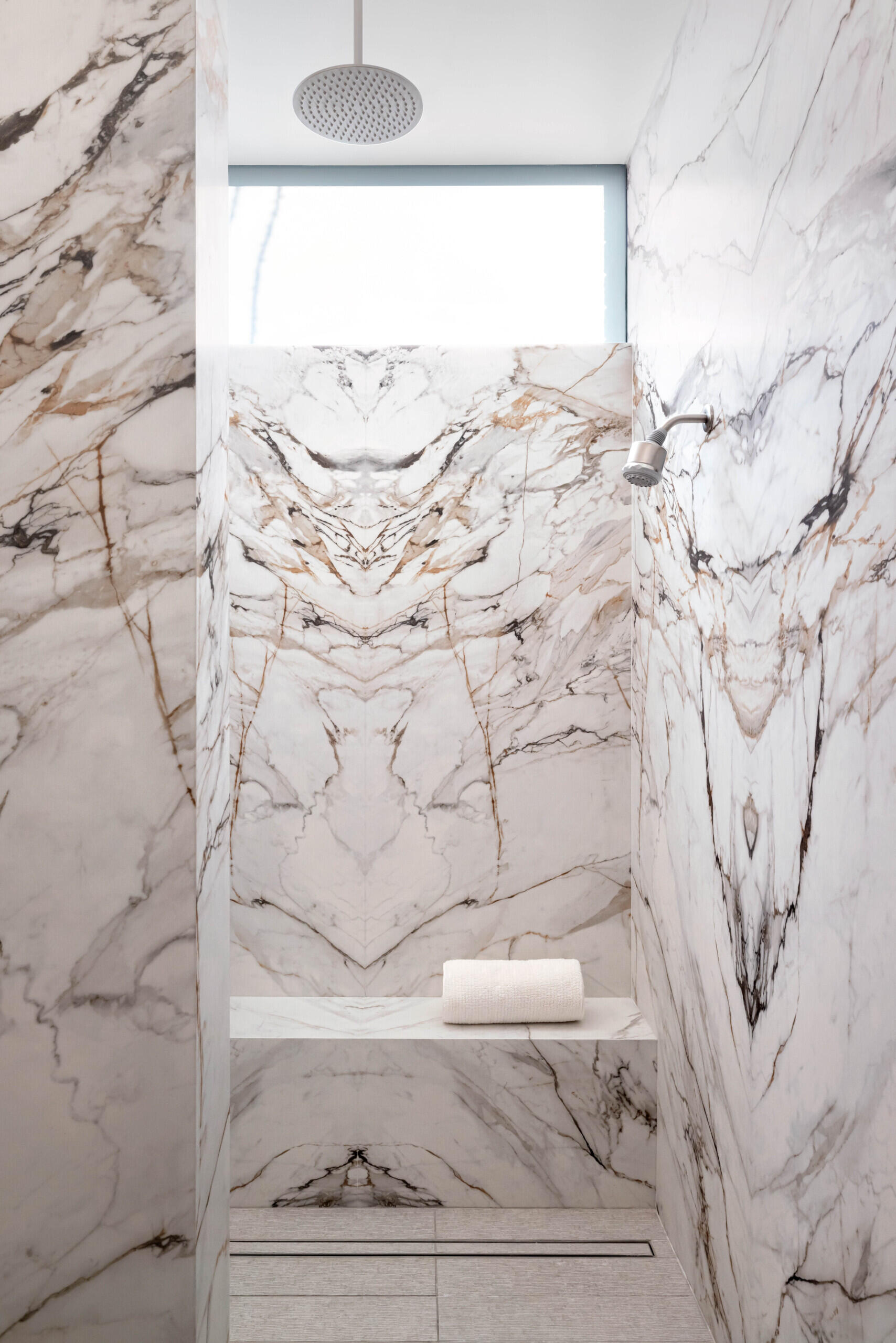 This bathroom blends luxury with nature, using stone and glass to bring in natural light while maintaining privacy. Clean lines and organic textures mirror the home’s overall aesthetic.